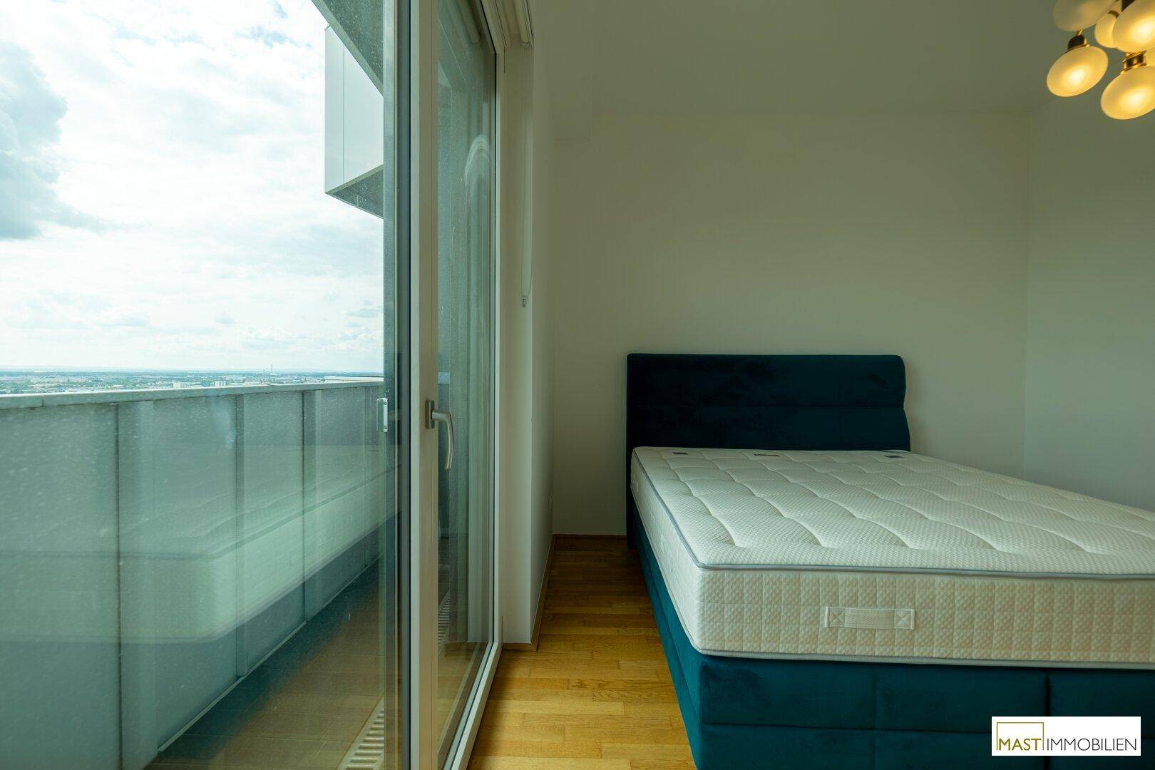 Schlafzimmer mit direktem Zugang zum Balkon durch große Glasfenster, bietet einen weiten Ausblick.