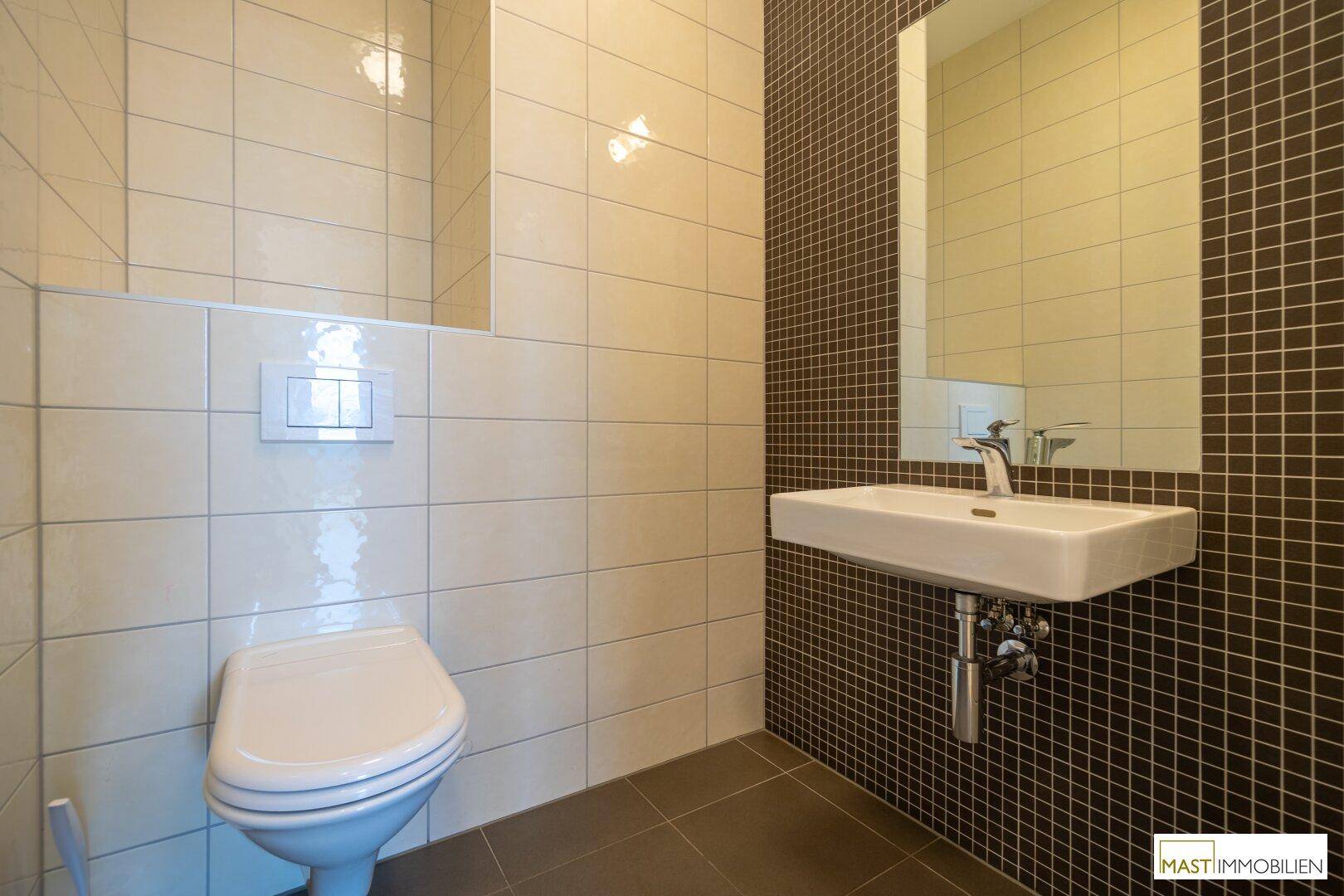 Gäste-WC mit Wand-WC, modernem Waschbecken und zweifarbigen Fliesen in Beige und Dunkelbraun.