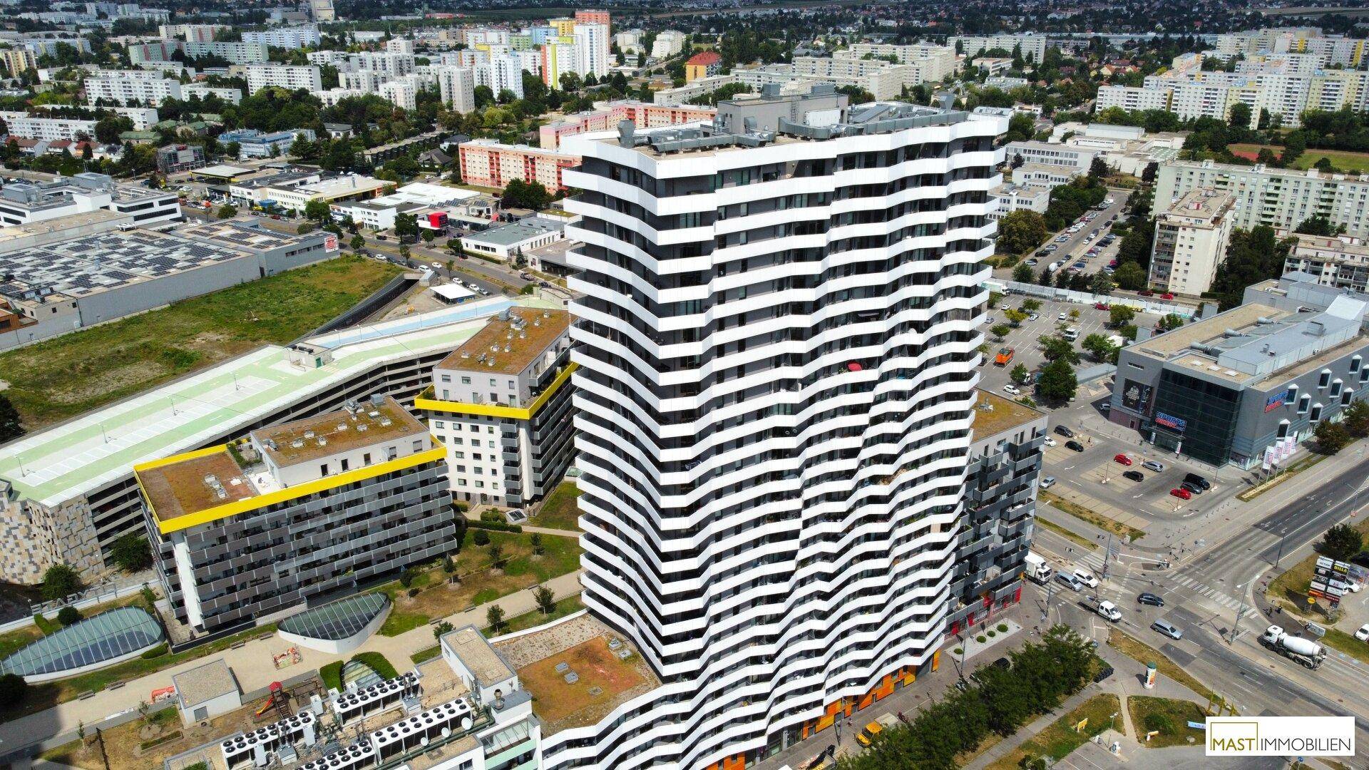Weitläufige Luftaufnahme eines modernen Hochhauses in einer dichten städtischen Umgebung mit vielen Gebäuden.