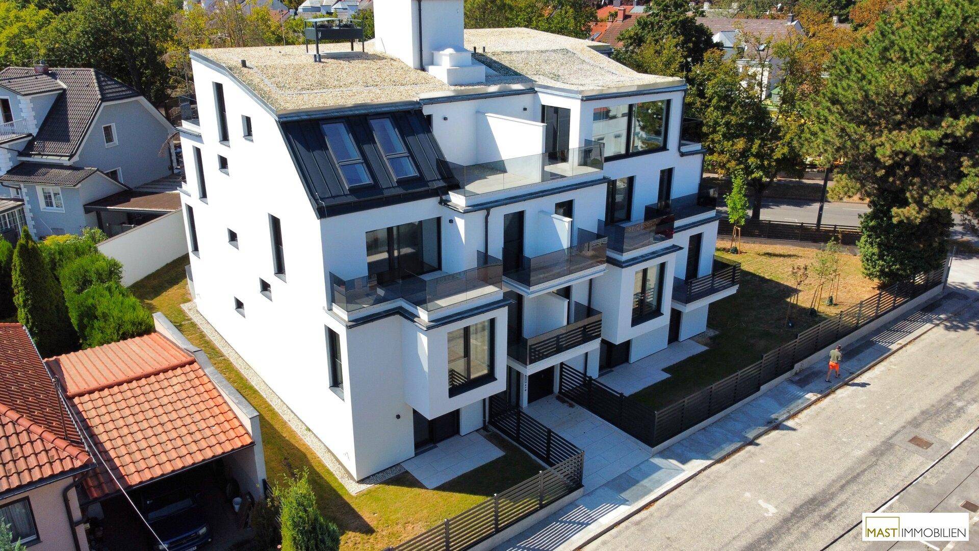 Moderne Wohnanlage mit Flachdach, Balkonen und großen Fensterfronten in grüner Umgebung.