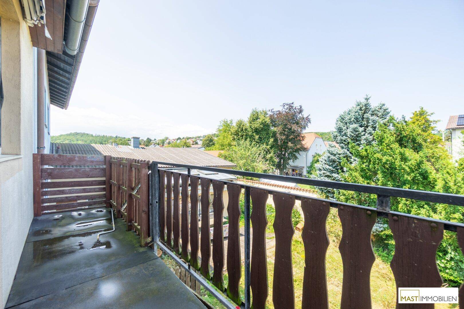 Balkon mit traditionellem Holzgeländer und Blick auf die umliegende grüne Landschaft.