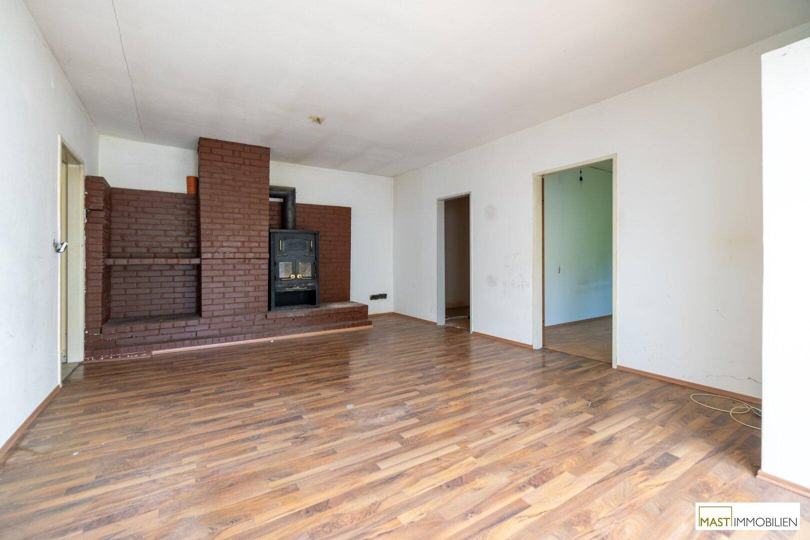 Wohnzimmer mit Laminatboden und einem gemauerten Kamin, der eine gemütliche Atmosphäre schafft.