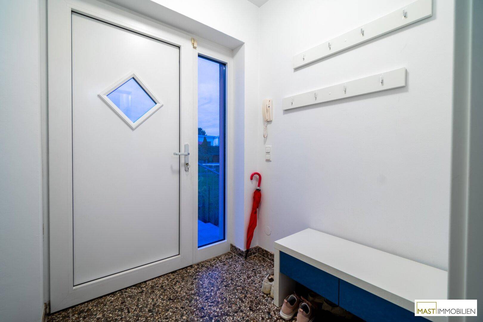 Heller Eingangsbereich mit moderner Haustür, Garderobe und Terrazzoboden.