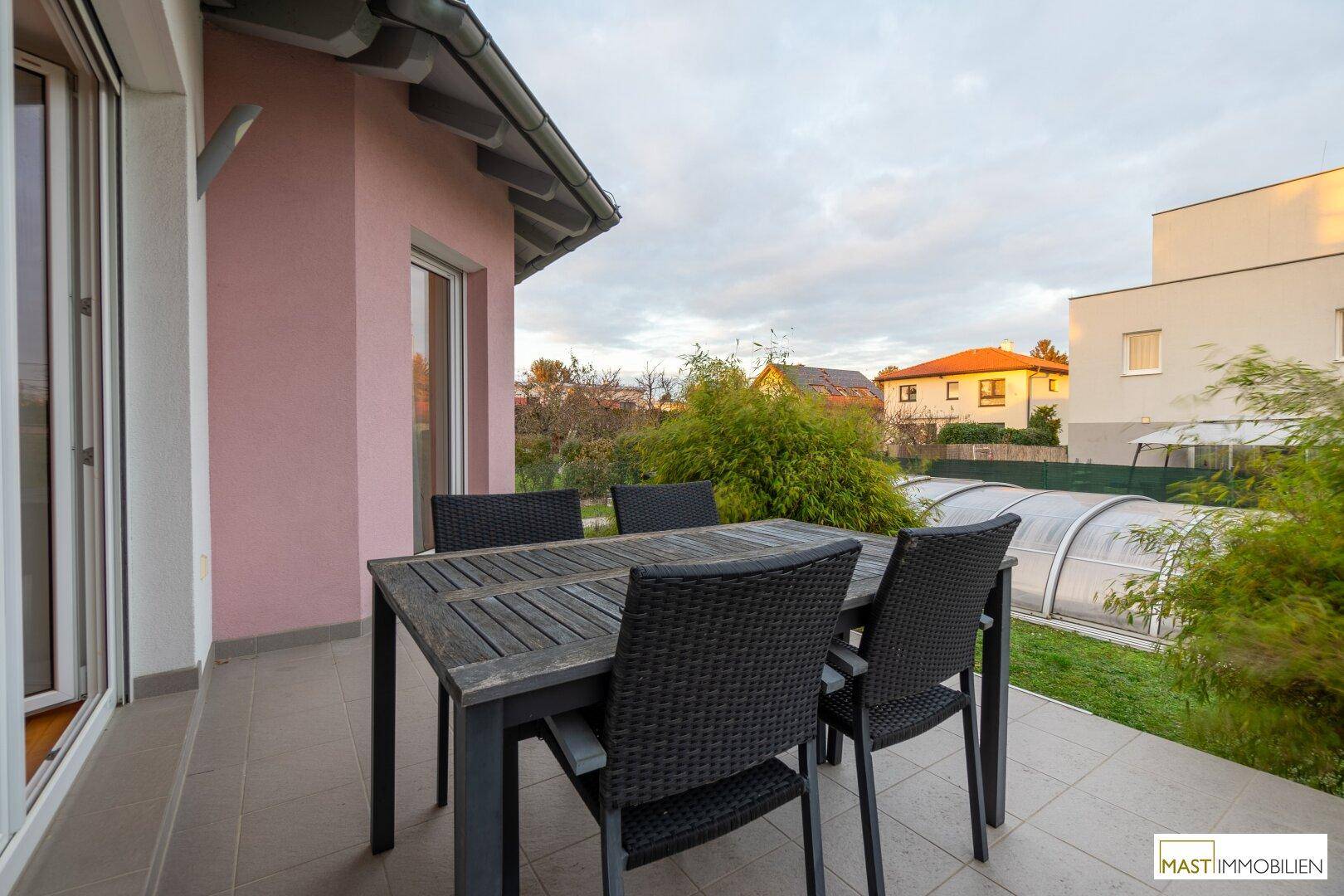 Terrasse am Haus mit Gartenmöbeln und Blick auf den Garten und den Poolbereich.