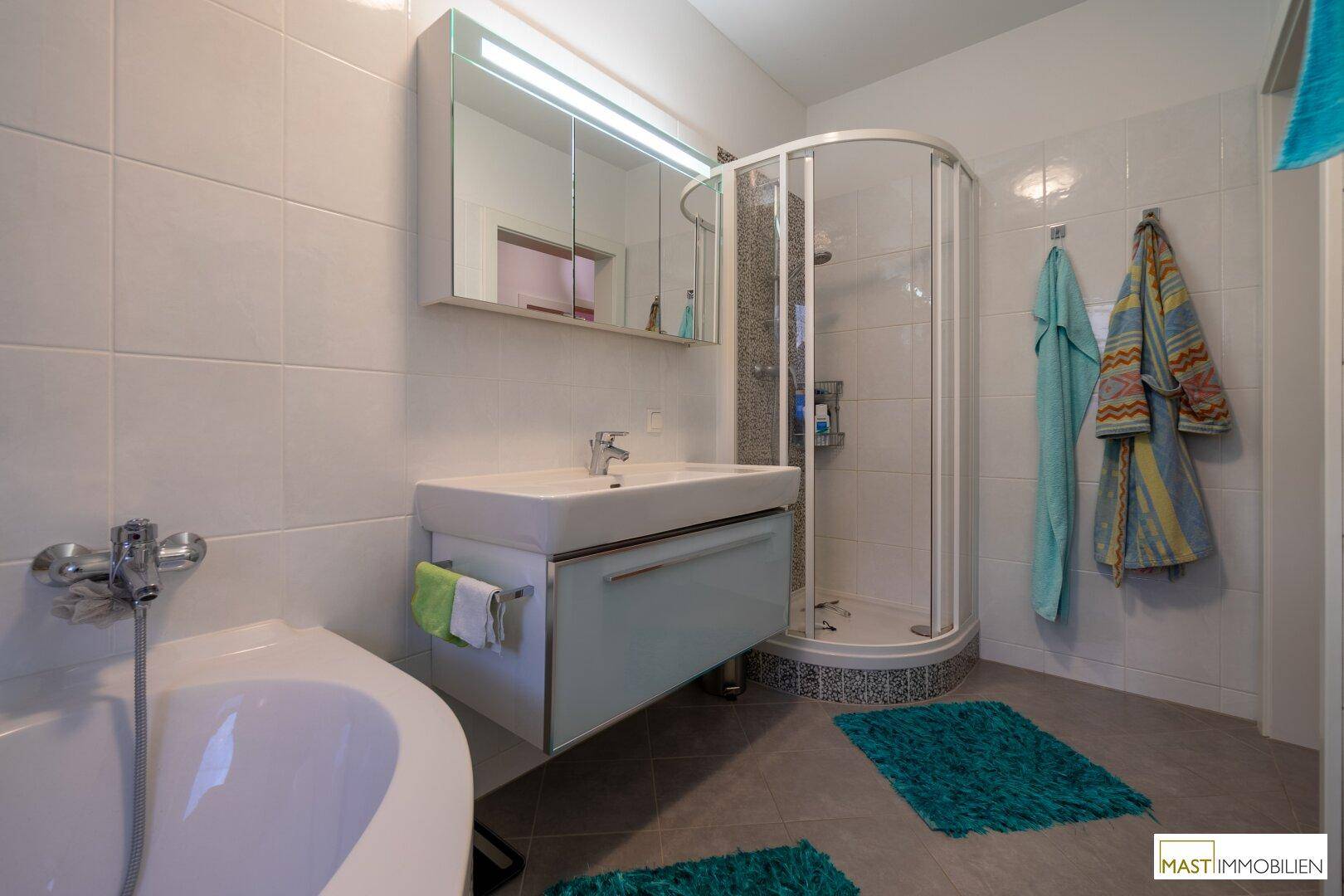 Modernes Badezimmer mit Dusche, Badewanne, Einzelwaschbecken und Spiegelschrank.