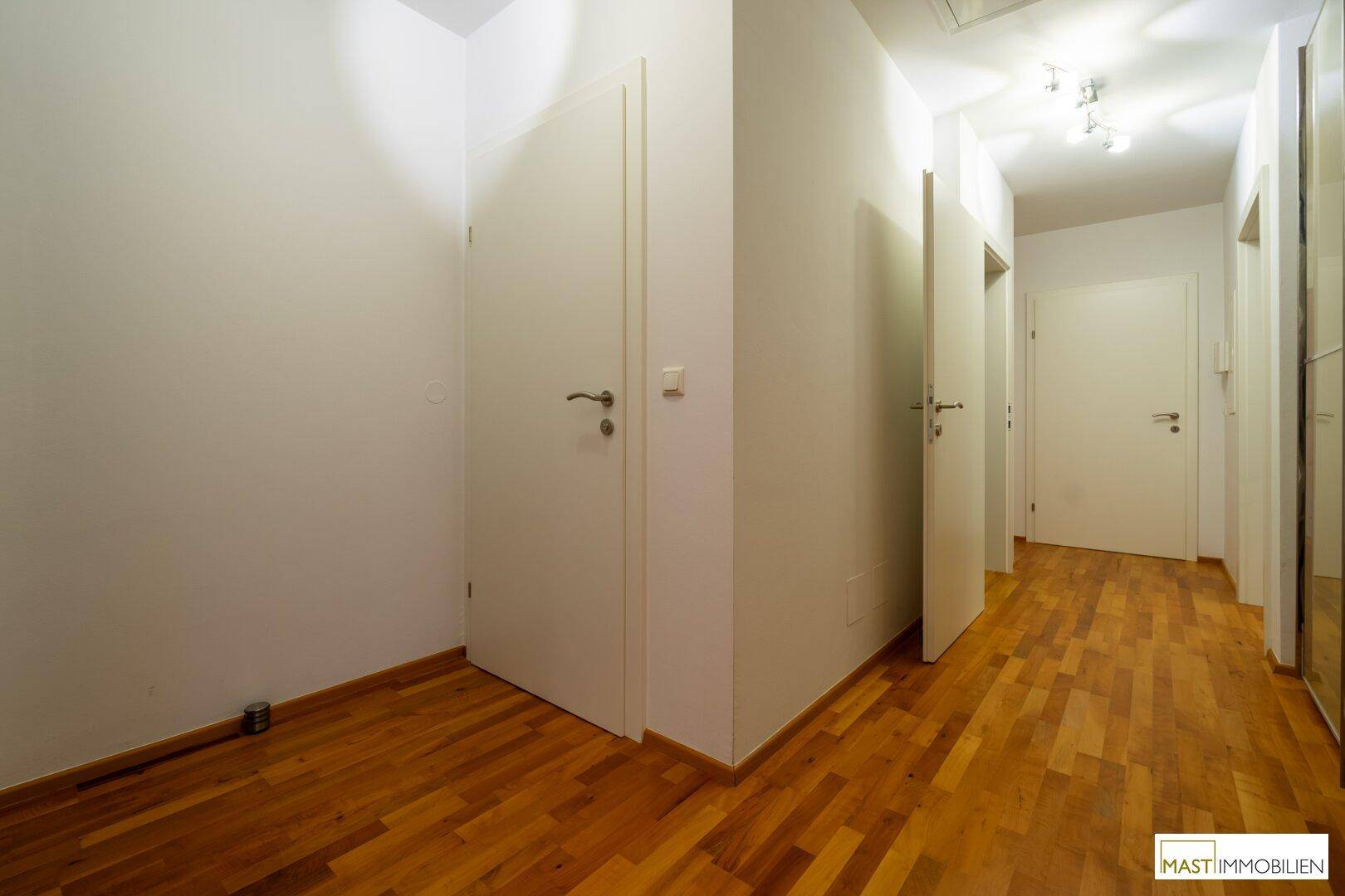 Langer Flur mit Holzboden und mehreren Türen zu den angrenzenden Räumen.