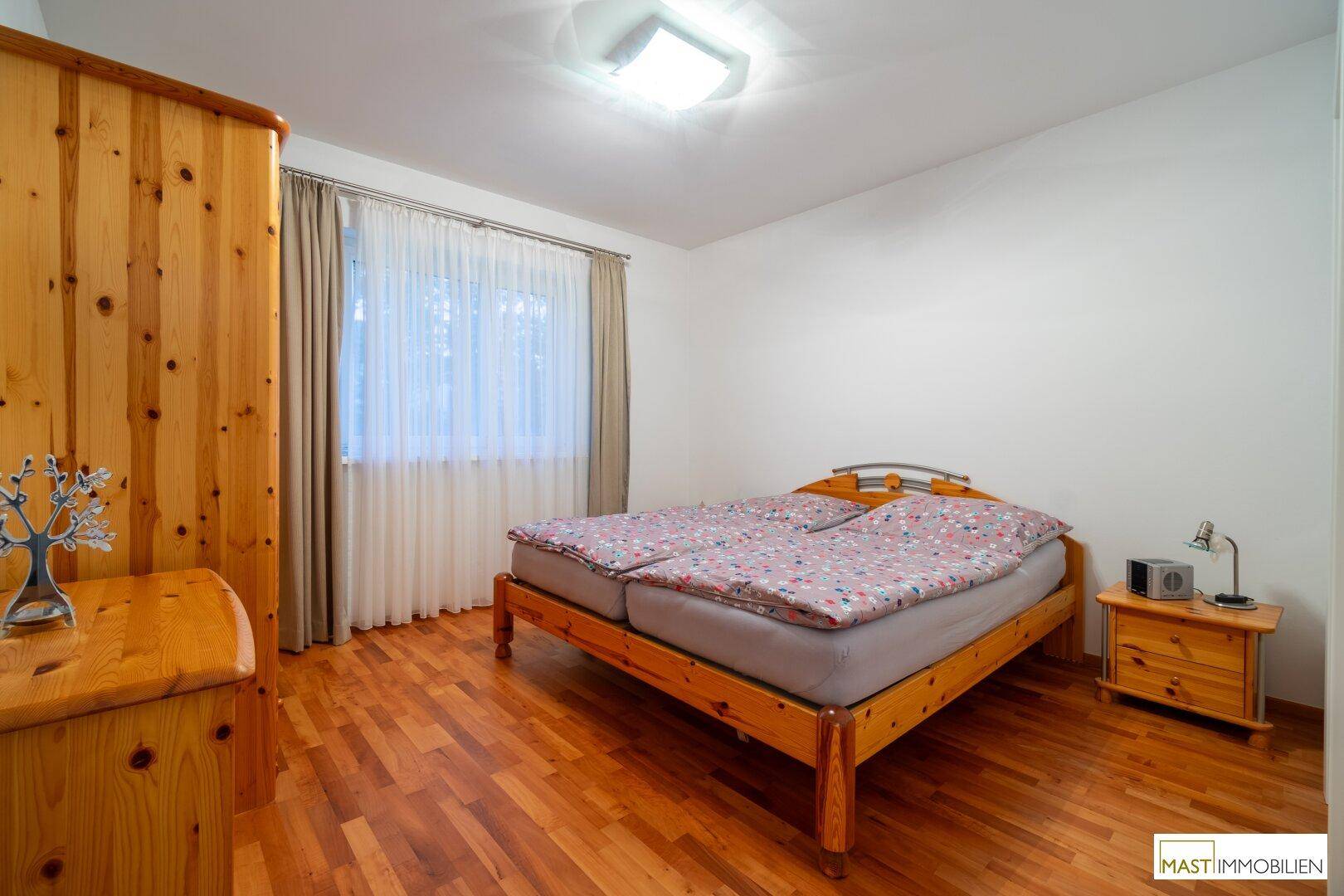 Schlafzimmer mit Holzbett, Holzschrank und Holzboden, hell und gemütlich eingerichtet.