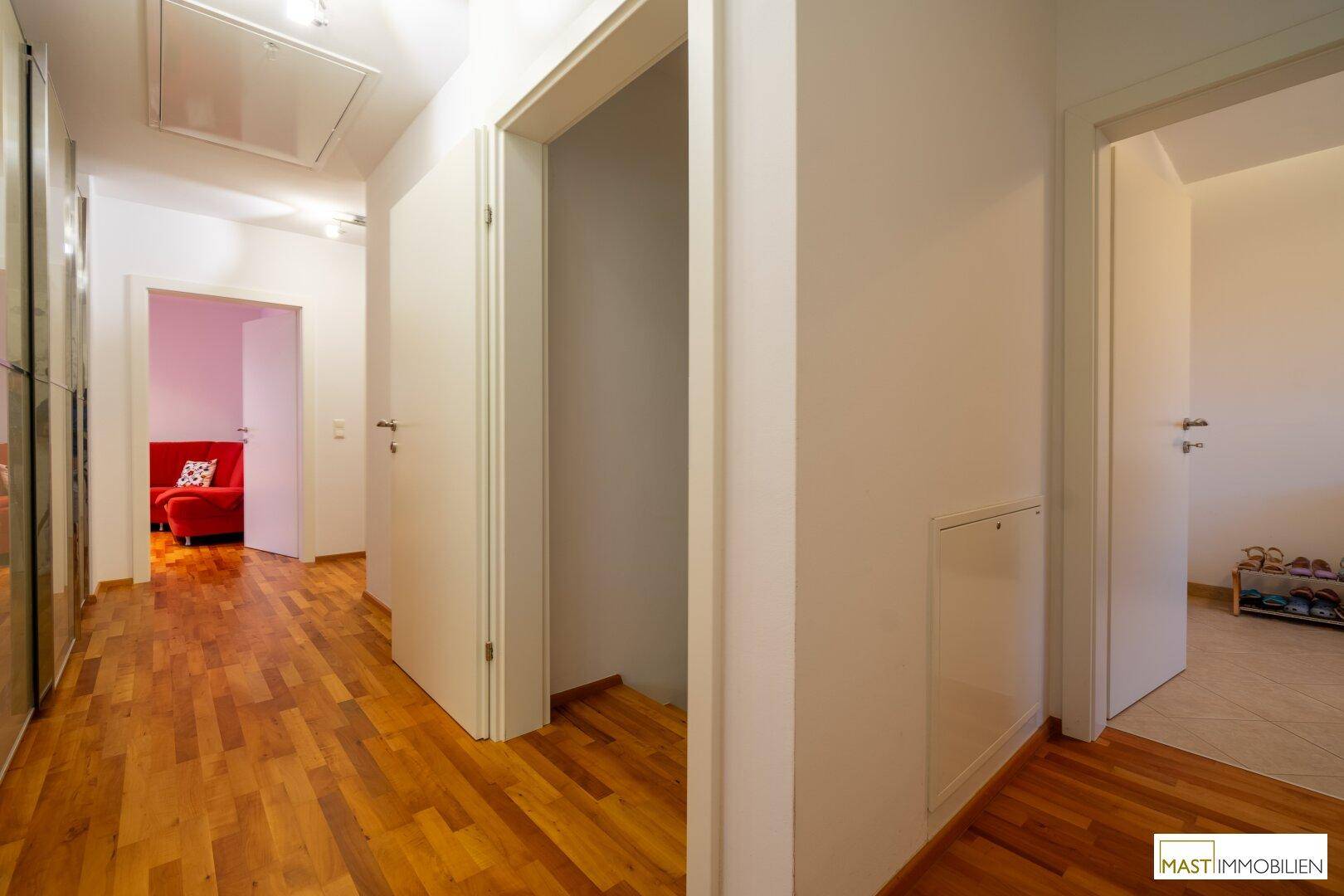 Heller Flur mit Holzboden, Einbauschränken und Zugang zu weiteren Räumen.