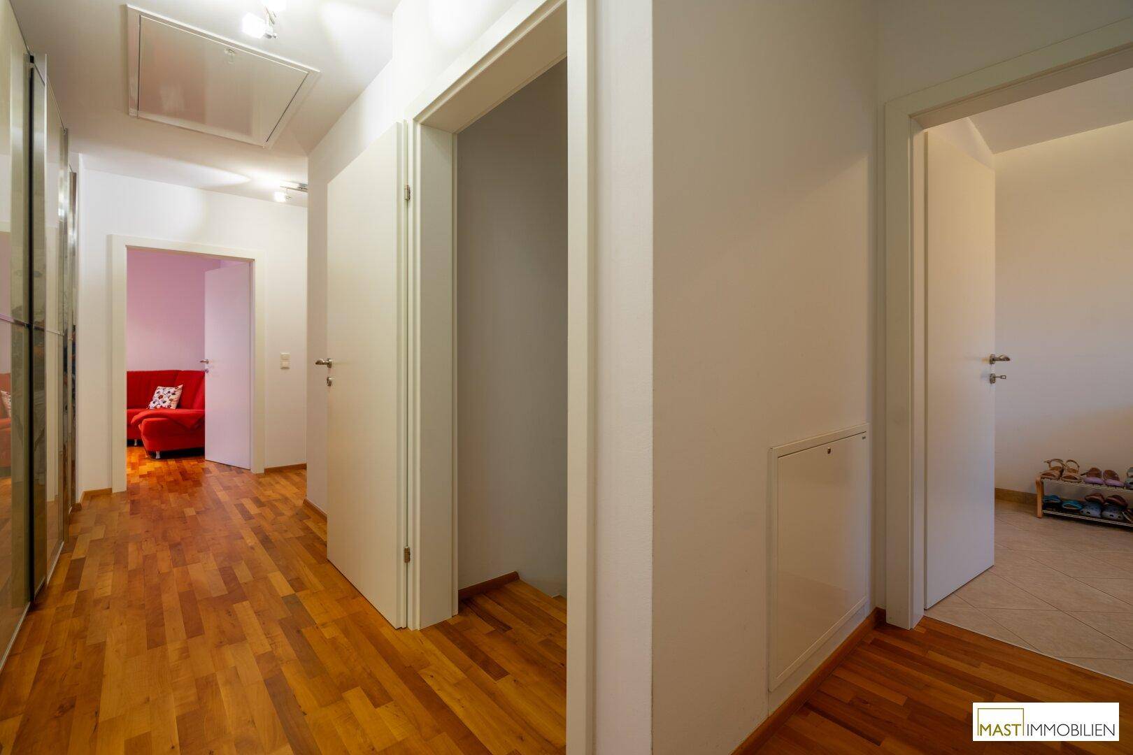 Heller Flur mit Holzboden, Einbauschränken und Zugang zu weiteren Räumen.