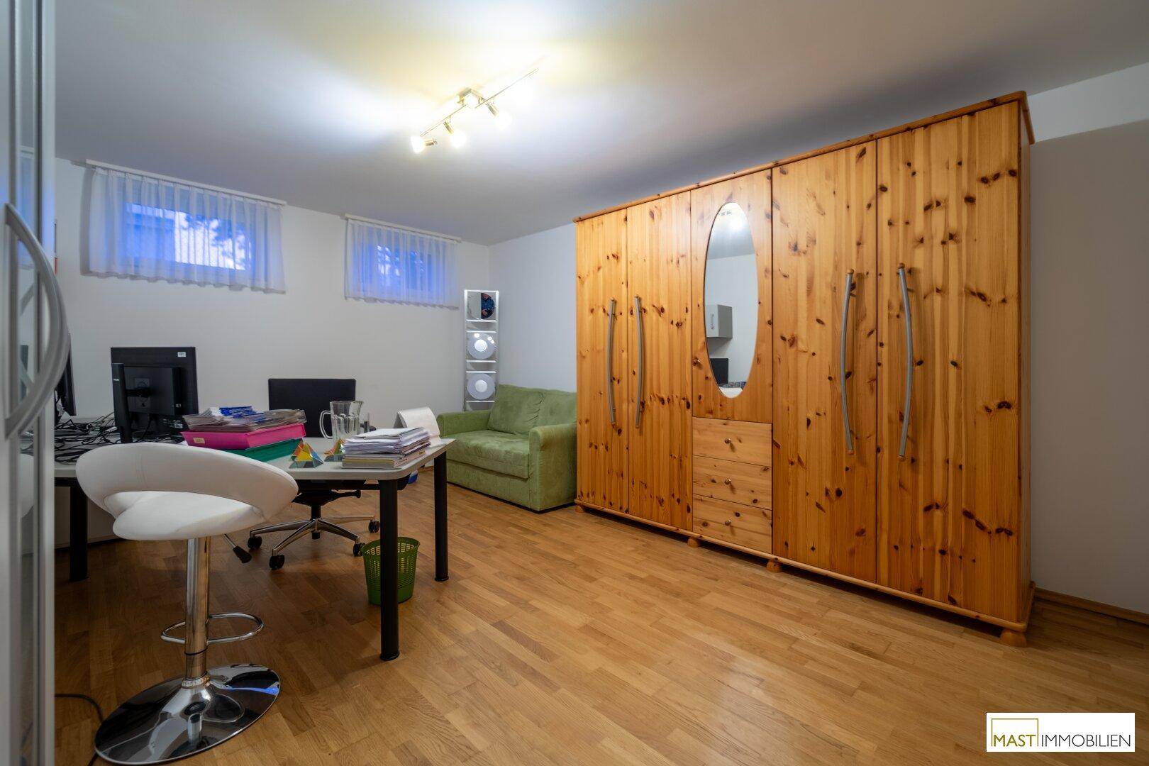 Büro im Untergeschoss mit Holzboden, großem Schrank und Arbeitsplätzen.