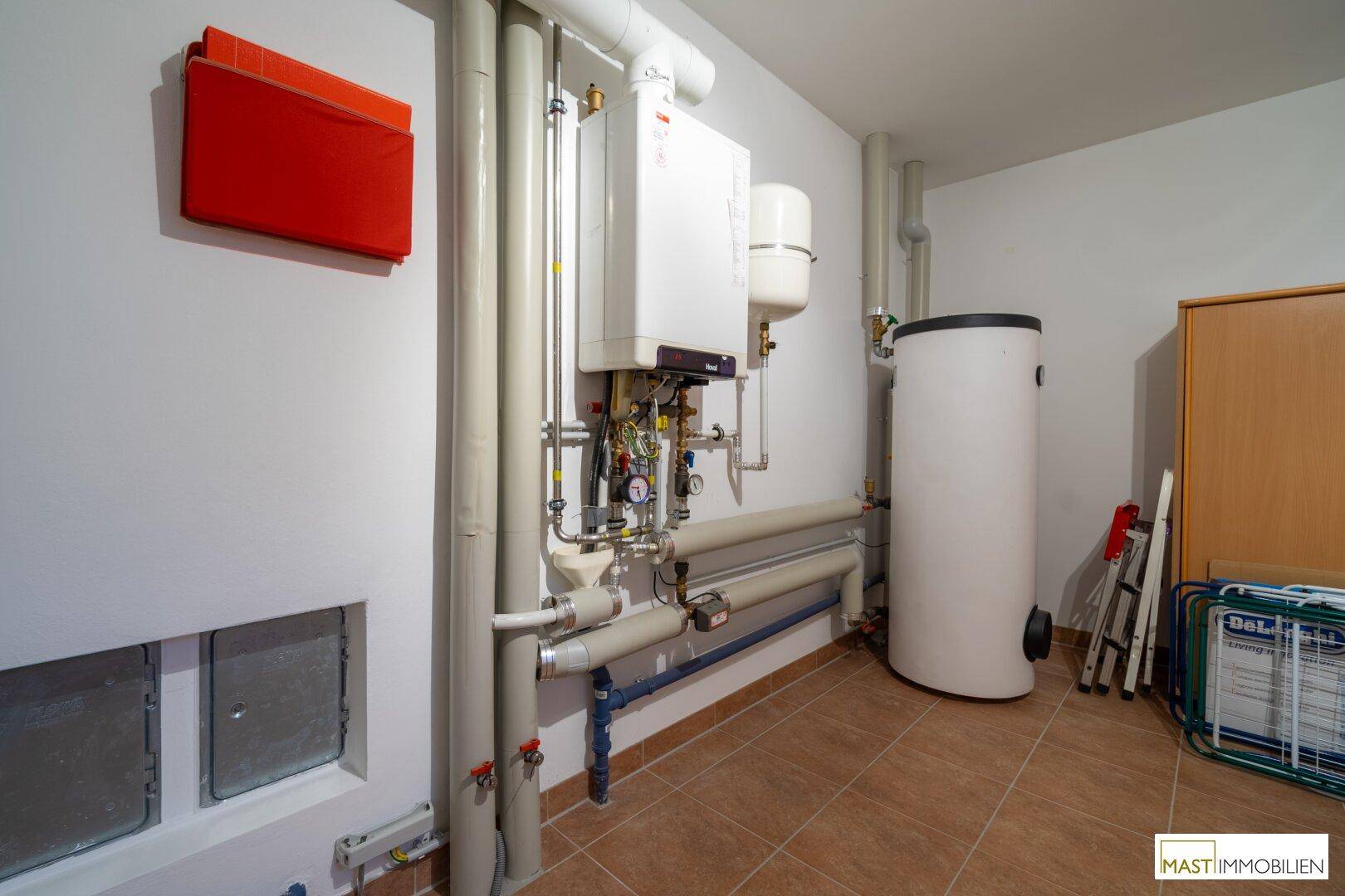 Heizungsraum im Keller mit moderner Heizungsanlage und Warmwasserspeicher.
