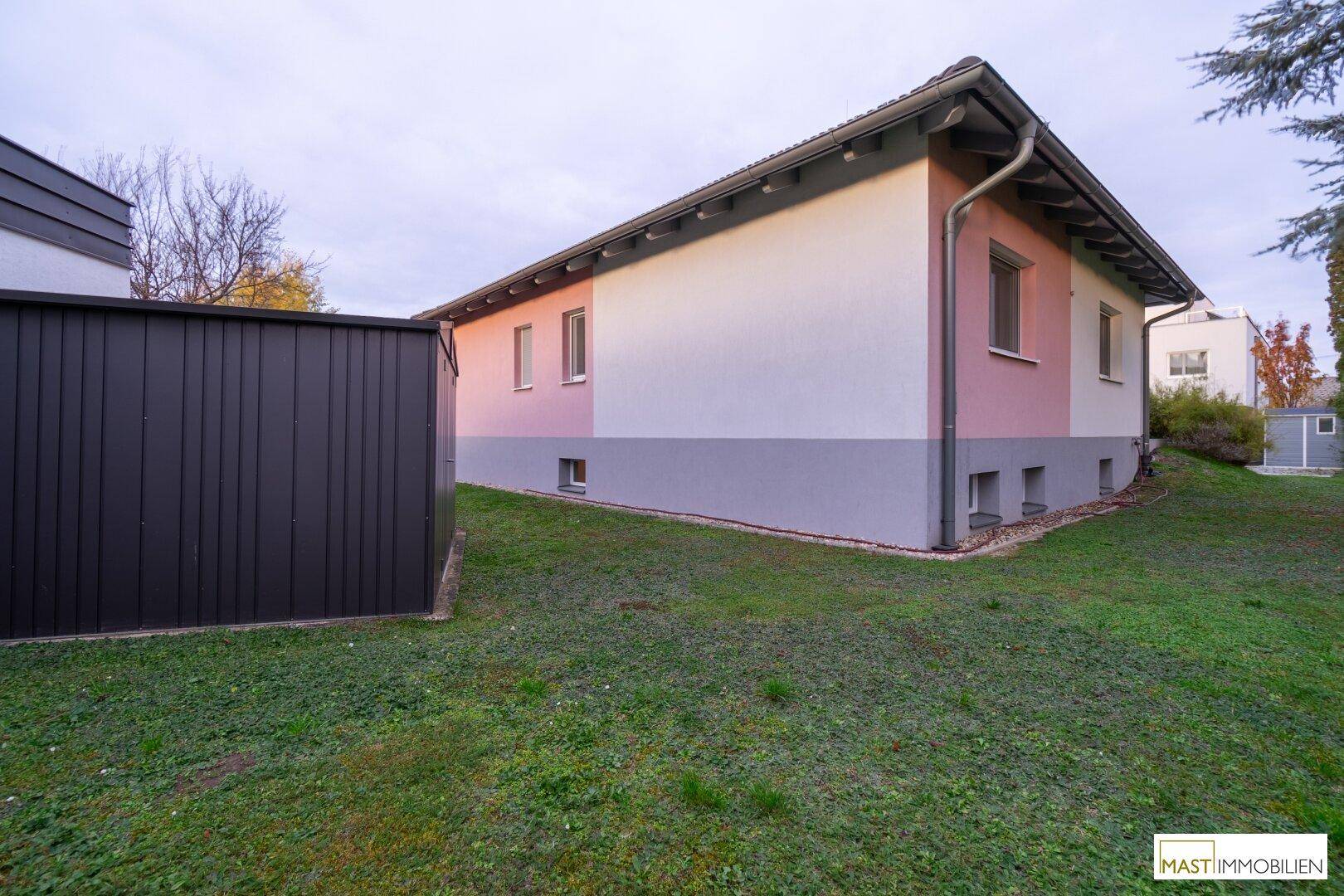 Gepflegter Gartenbereich neben dem Haus mit Rasenfläche und Gartenhaus.