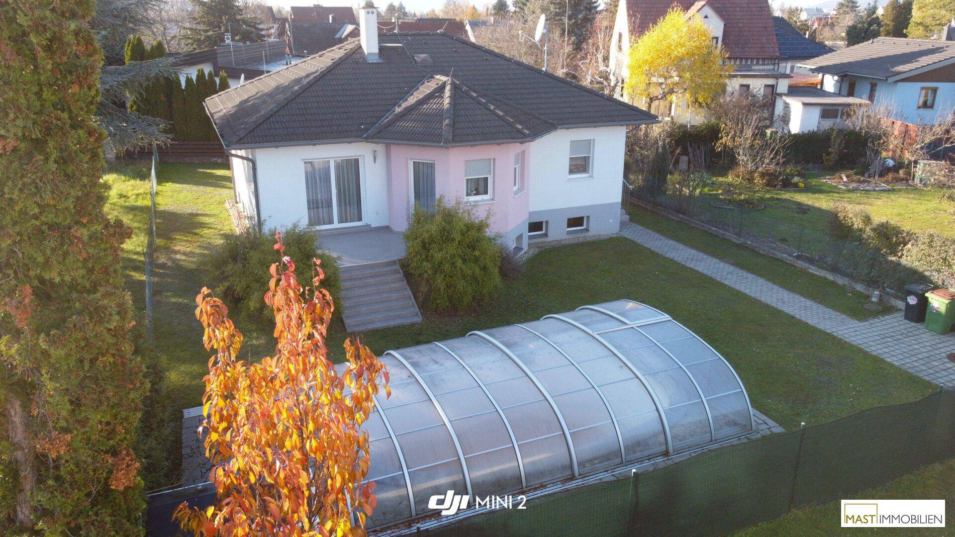 Luftaufnahme des Einfamilienhauses mit großem Garten und überdachtem Poolbereich.