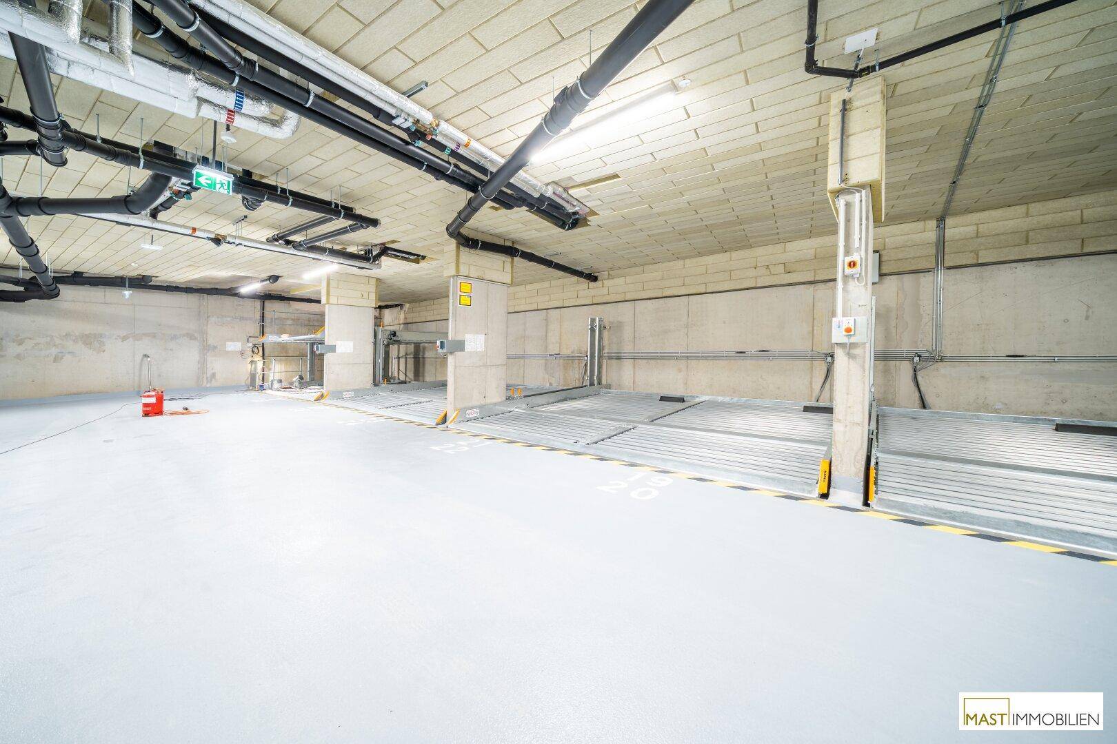 Tiefgarage mit modernen Parksystemen und Betonwänden, gut beleuchtet und geräumig.