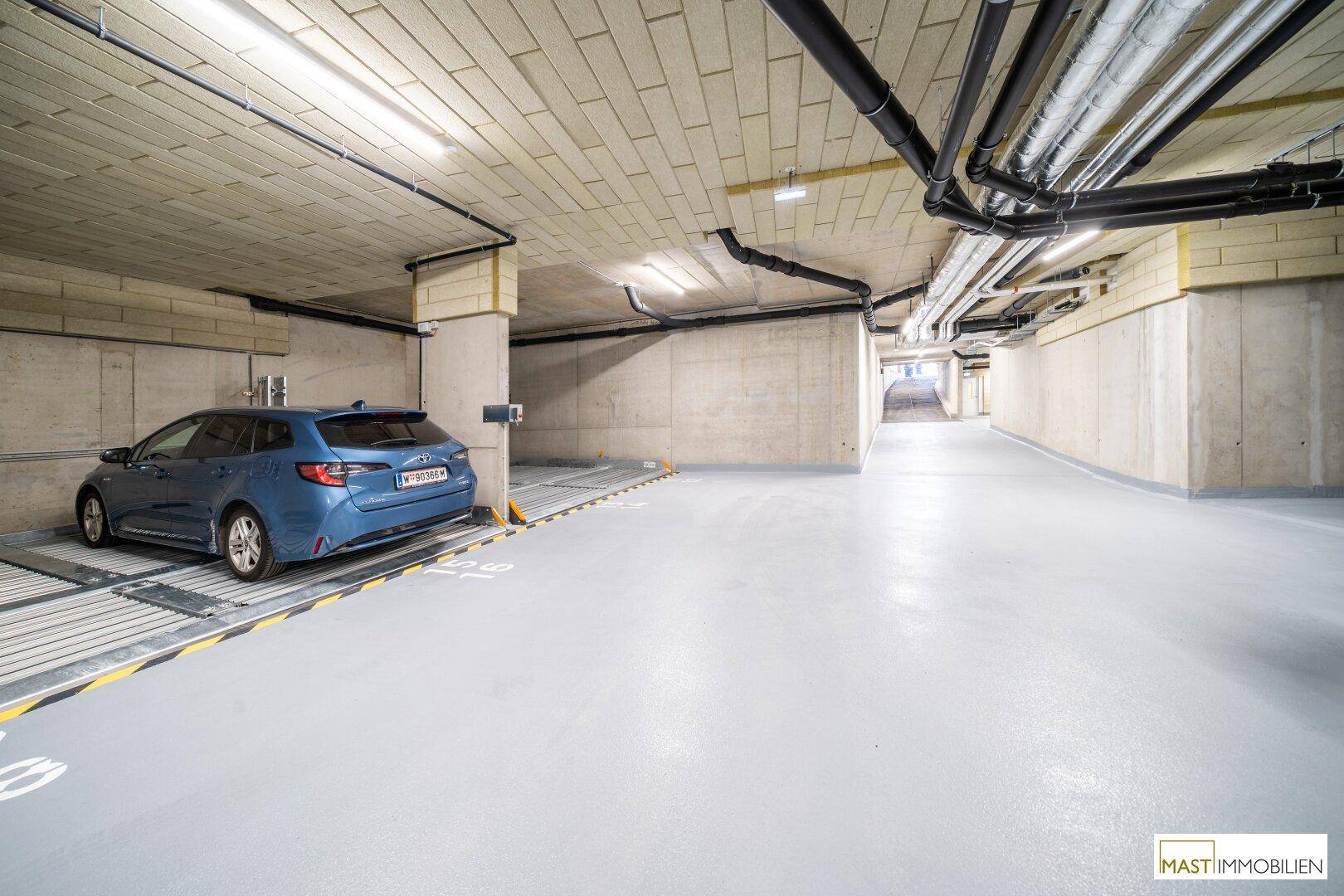 Geräumige Tiefgarage mit einem geparkten Auto und effizienten Parksystemen für Bewohner.