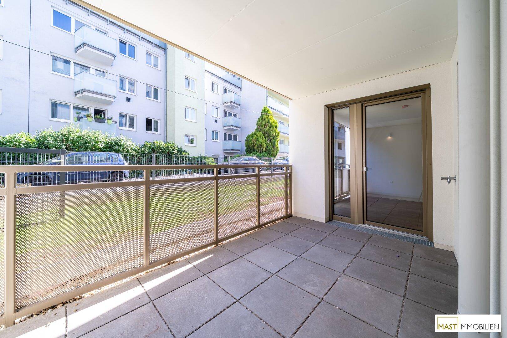 Geräumiger Balkon mit Fliesenboden und Blick auf die umliegenden Gebäude und die Straße.