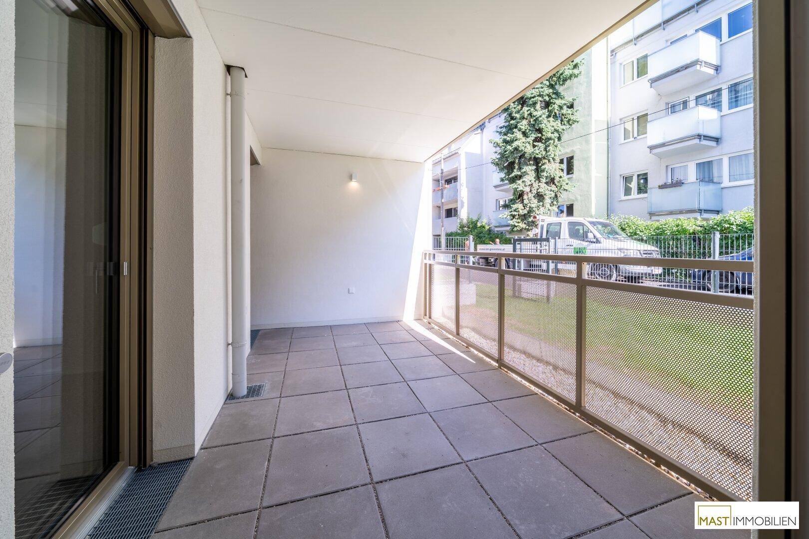 Heller Balkon mit Fliesenboden und moderner Metallbrüstung, ideal zum Entspannen im Freien.