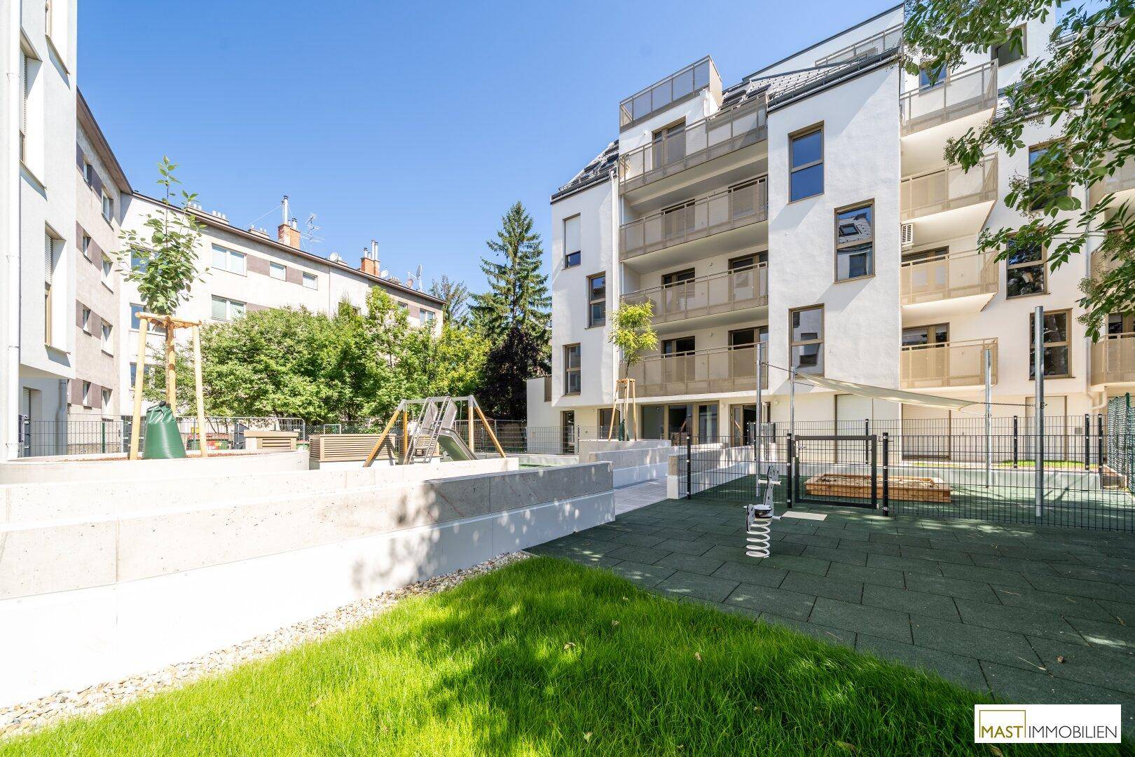 Innenhof des Wohnkomplexes mit Spielplatz und gepflegten Grünflächen für die Bewohner.