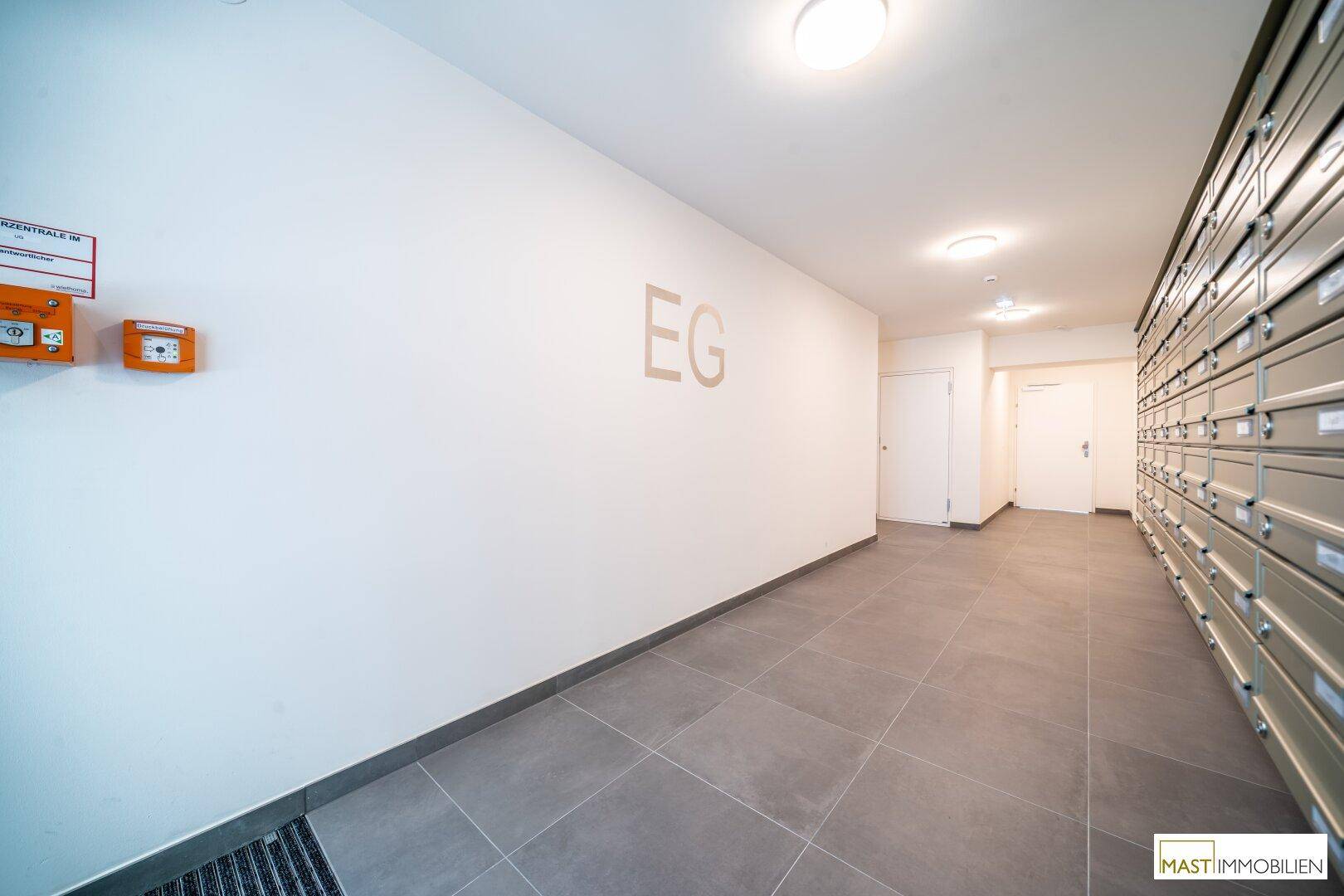 Heller Eingangsbereich mit Briefkästen und Fliesenboden im Erdgeschoss des Gebäudes.