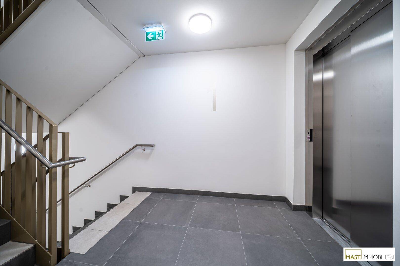 Treppenhaus mit modernem Geländer und Aufzug in einem hellen, gepflegten Zustand.