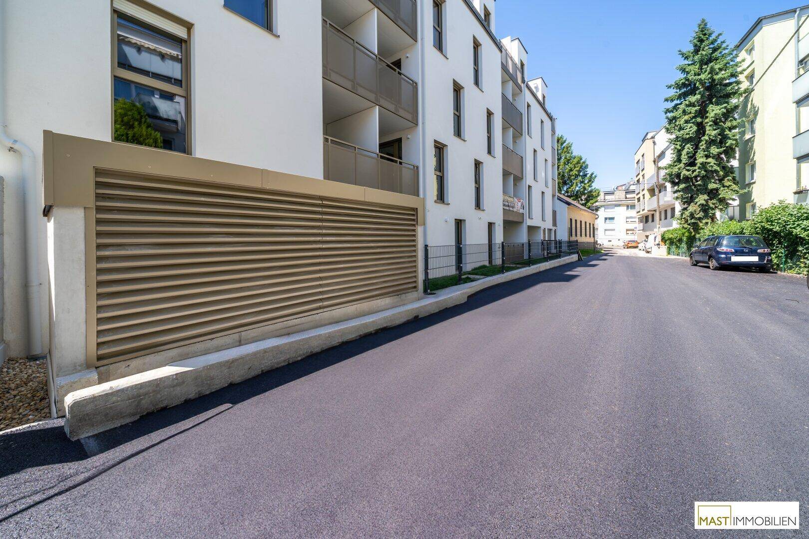 Ansicht der modernen Wohnanlage von der Straße mit Zufahrt und gepflegter Umgebung.