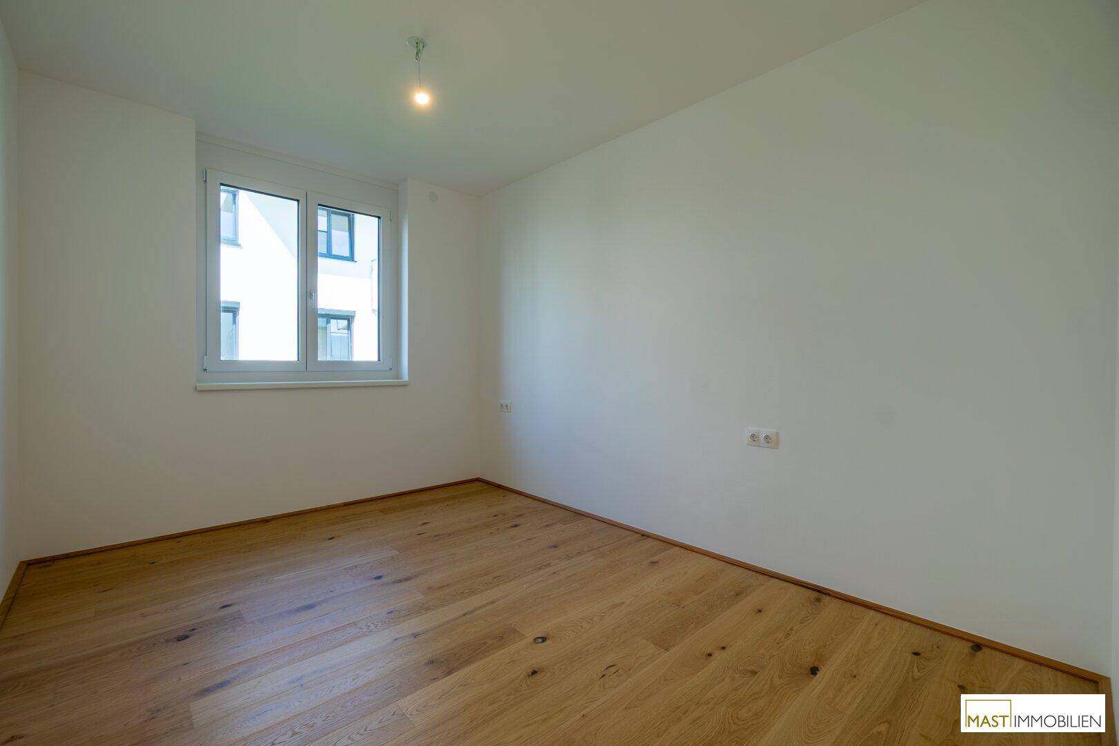 Weiteres helles Zimmer mit Holzparkett und Fenster, ideal als Schlaf- oder Arbeitszimmer.