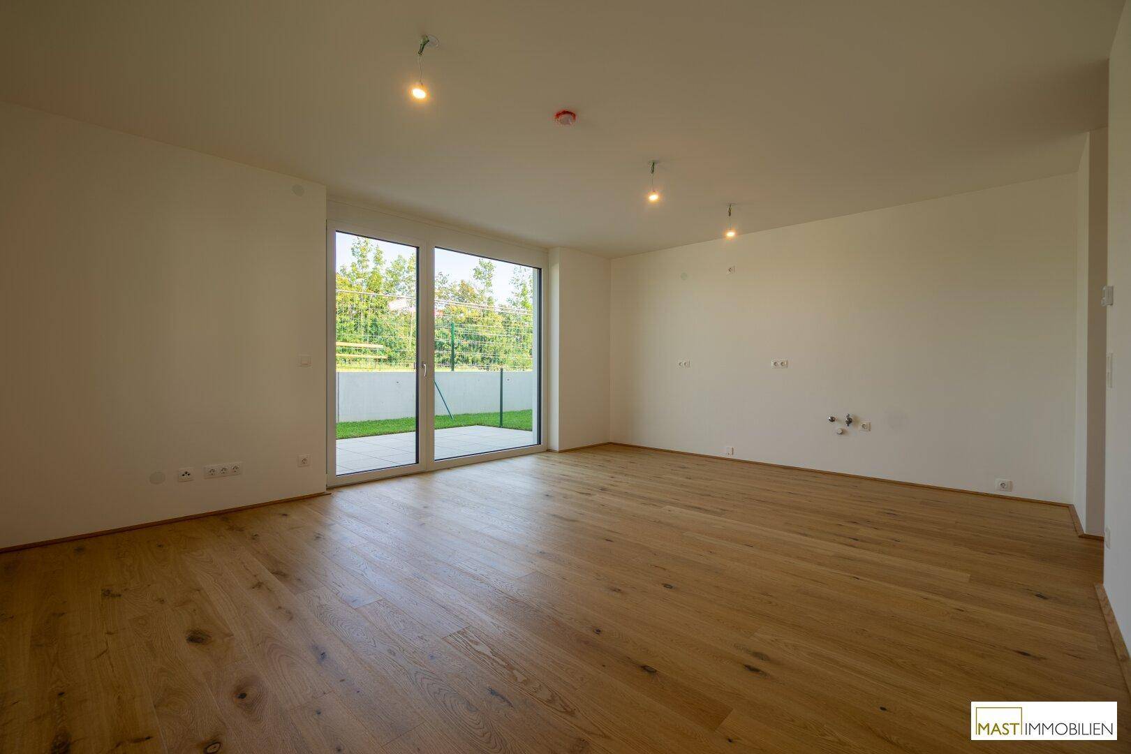 Helles Wohnzimmer mit Echtholzparkett und großer Schiebetür zum Außenbereich.