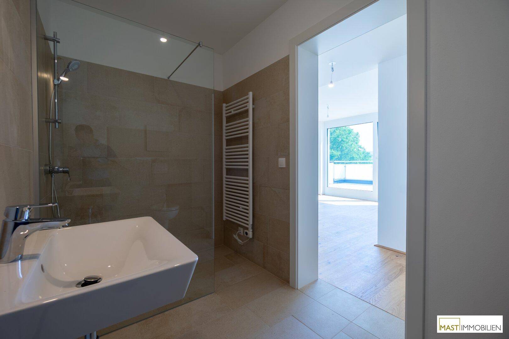 Helles Badezimmer mit modernem Waschbecken, Dusche und einem praktischen Handtuchheizkörper.