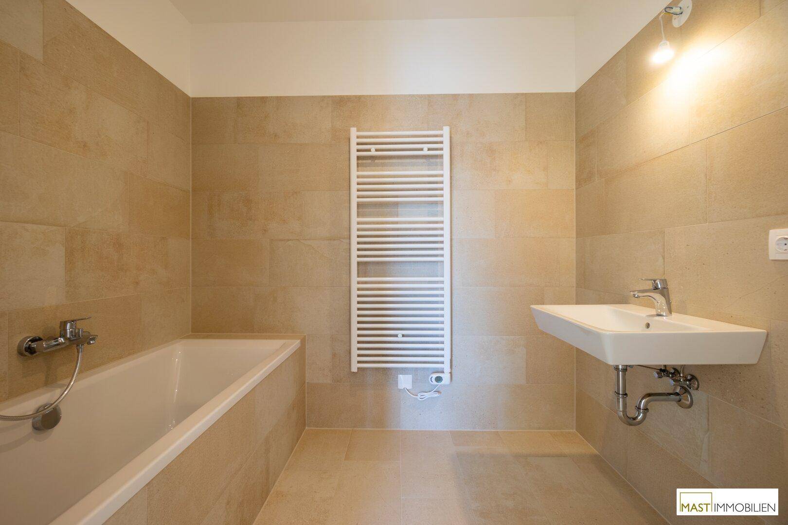 Geräumiges Badezimmer mit Badewanne, modernem Waschbecken und einem beheizten Handtuchhalter.