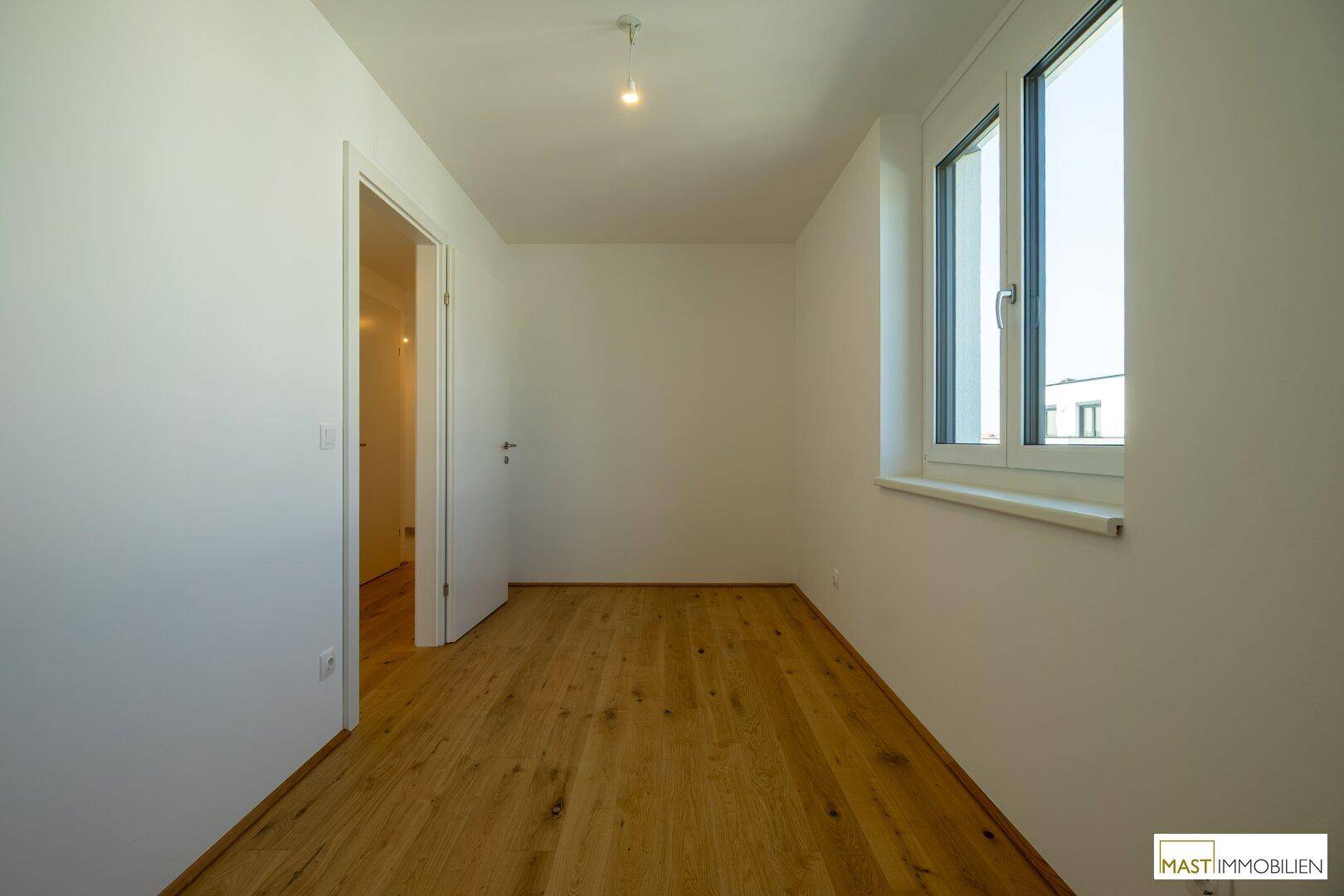 Freundliches Zimmer mit Holzboden und einem Fenster, das für gute Belichtung sorgt.
