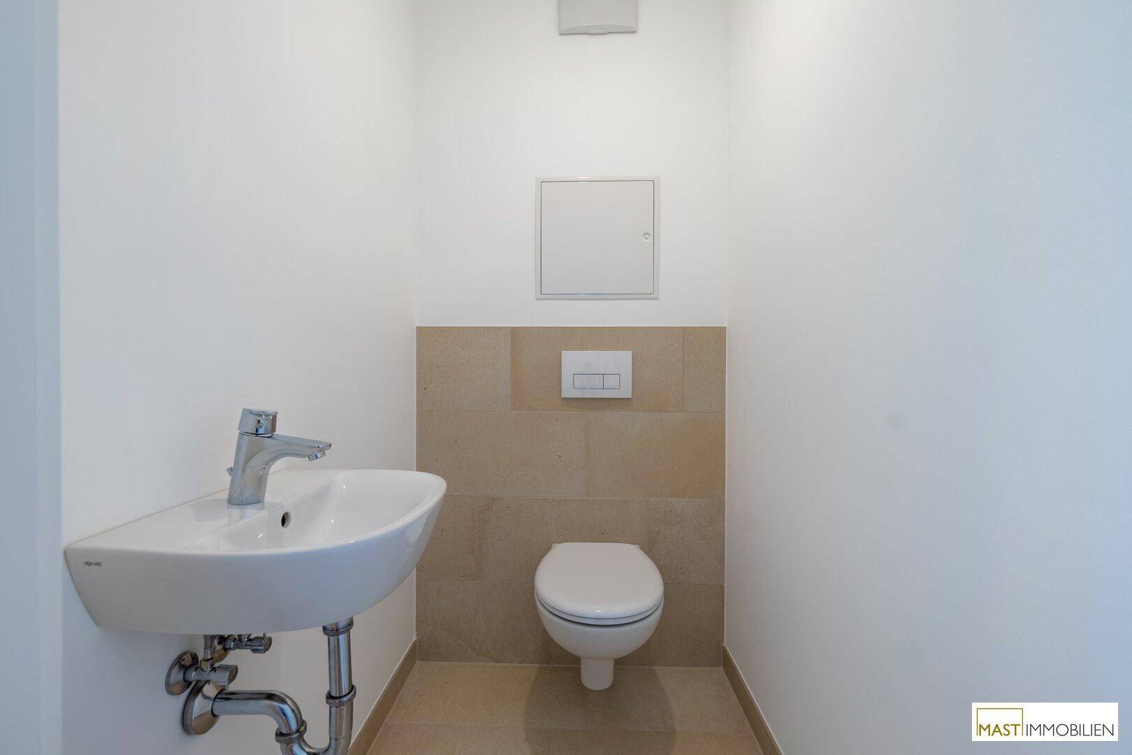 Kleines Gäste-WC mit modernem Wand-WC und Handwaschbecken, in hellen Farbtönen gehalten.