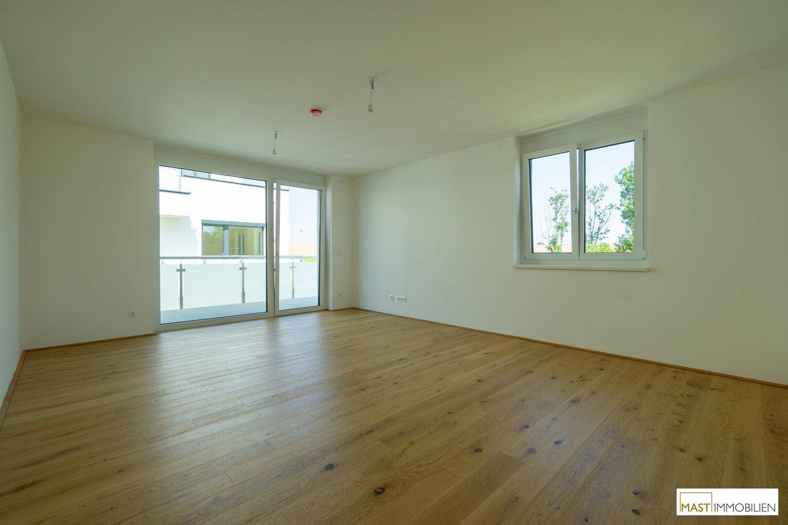 Helles Wohnzimmer mit Eichenparkett und großem Balkonzugang, ideal für natürliches Licht.