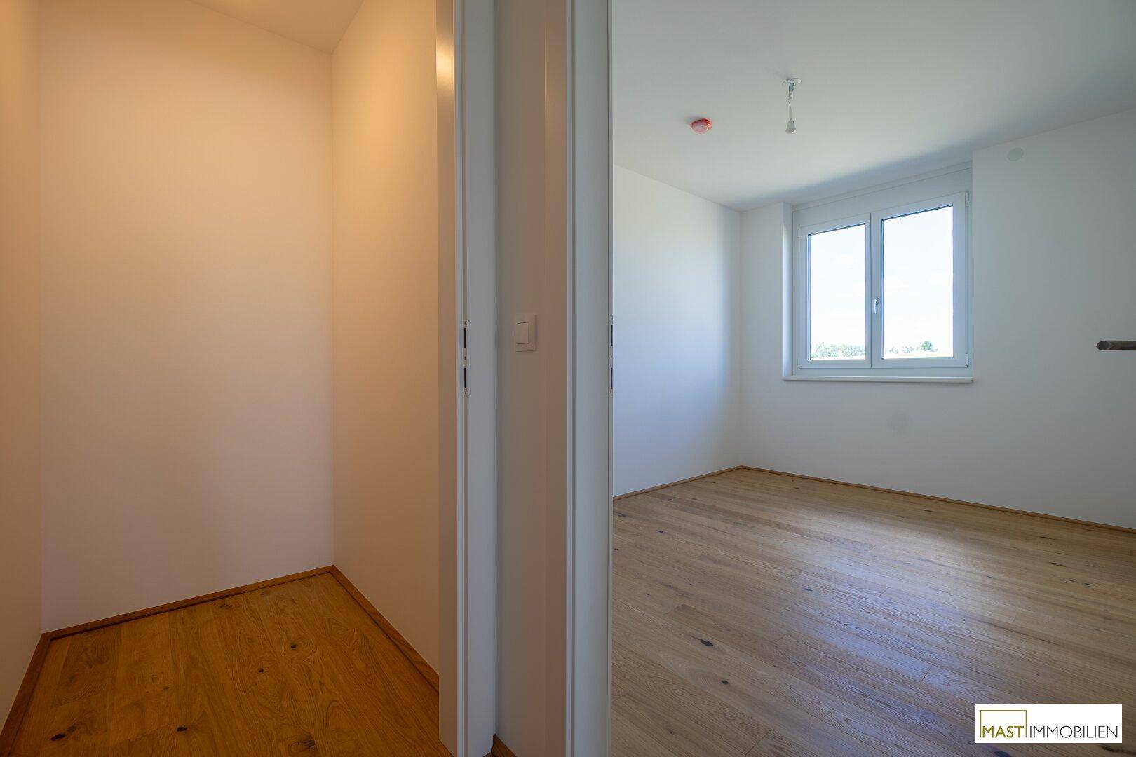 Flur mit Zugang zu einem hellen Zimmer und einem praktischen Abstellbereich.