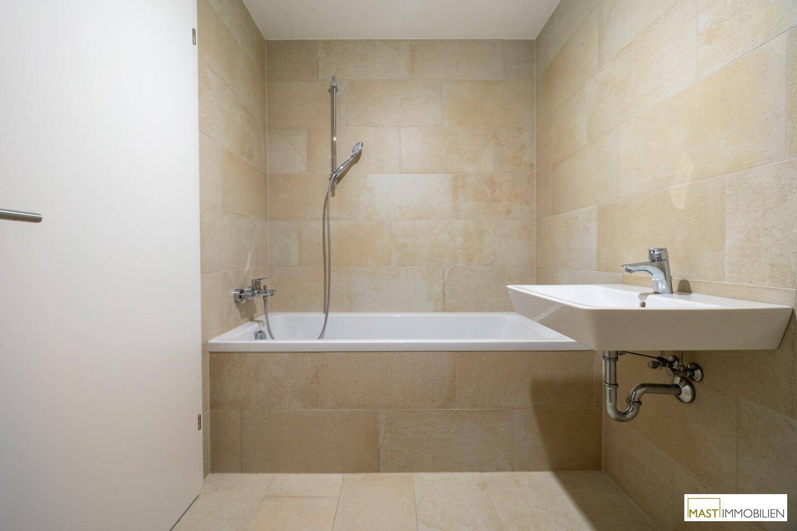 Modernes Badezimmer mit Badewanne, integrierter Dusche und beigefarbenen Fliesen.