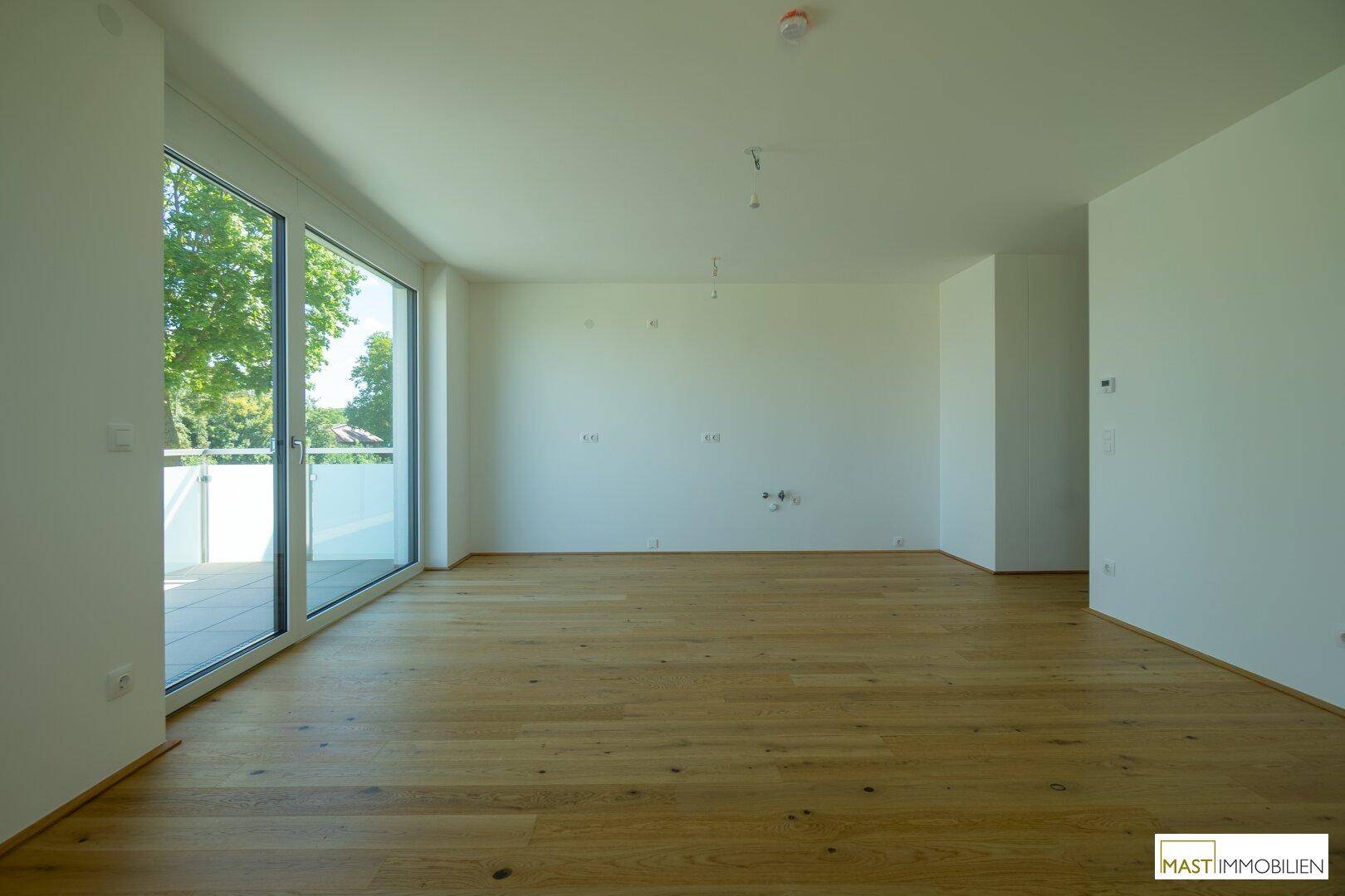 Helles Wohnzimmer mit Eichenparkett und großen Fenstern, die viel Tageslicht hereinlassen.