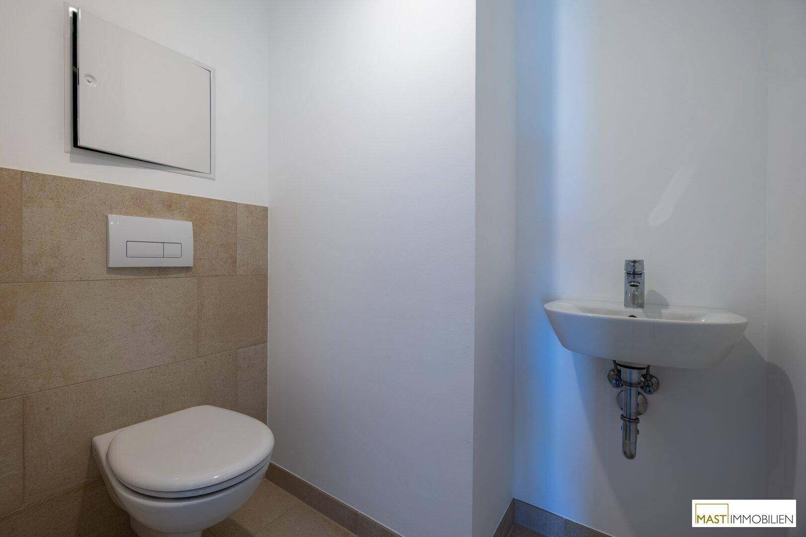 Separates WC mit wandhängender Toilette und kleinem Handwaschbecken, in modernem Design.