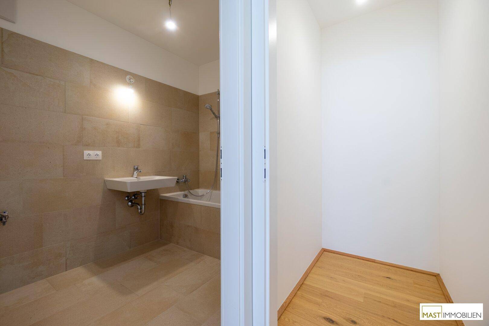 Modernes Badezimmer mit beigefarbenen Fliesen, Waschbecken und integrierter Badewanne.