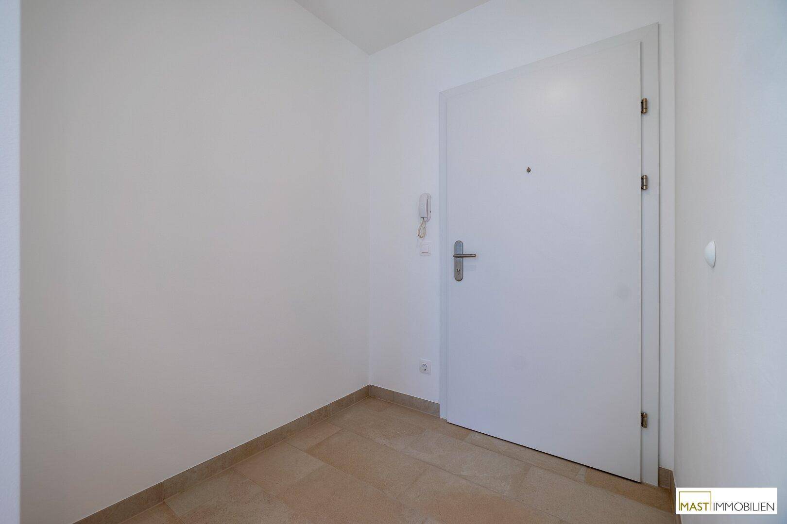 Sauberer Eingangsbereich mit Fliesenboden und weißer Wohnungstür.