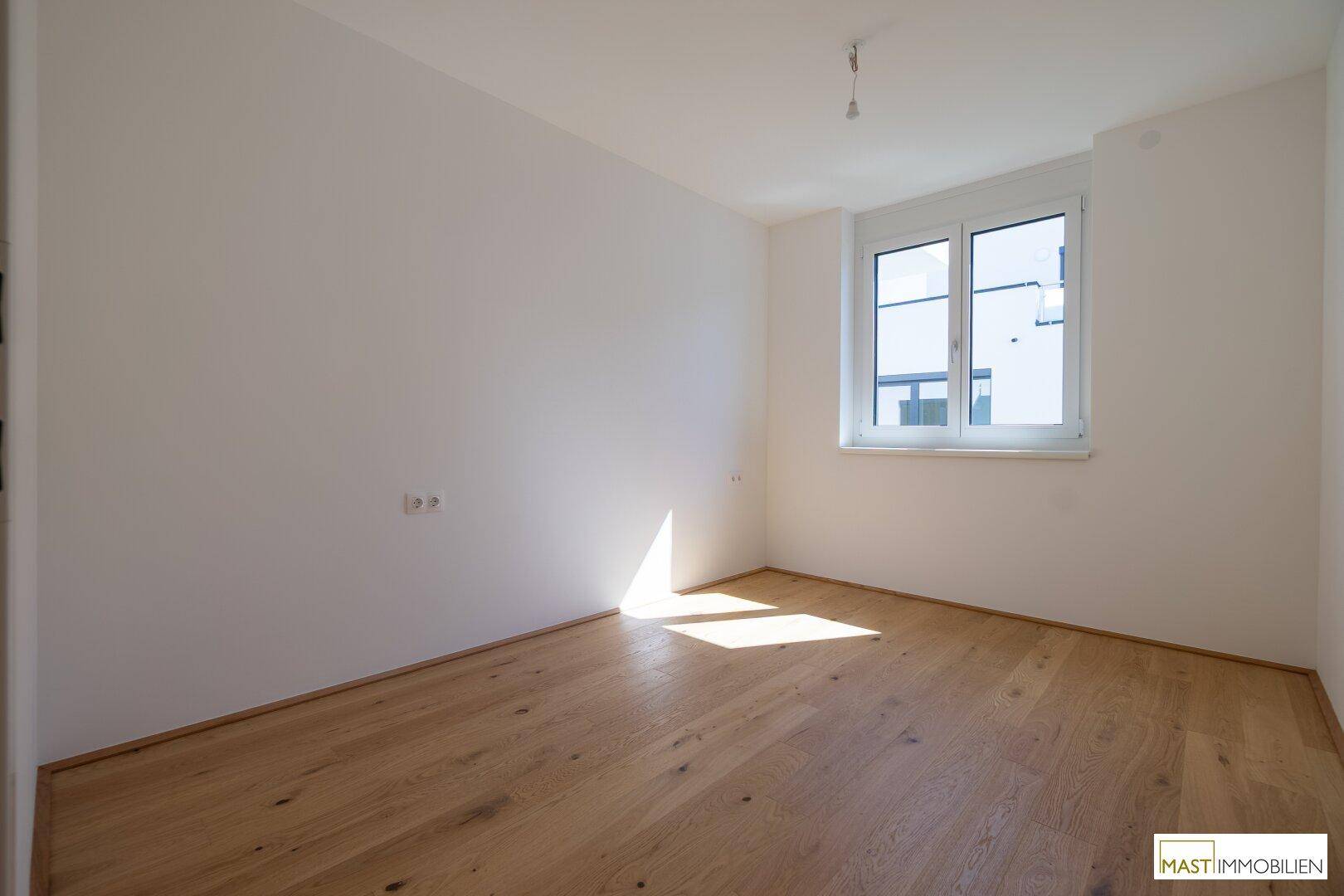Heller Raum mit Holzboden und Fenster, ideal als Schlaf- oder Kinderzimmer.