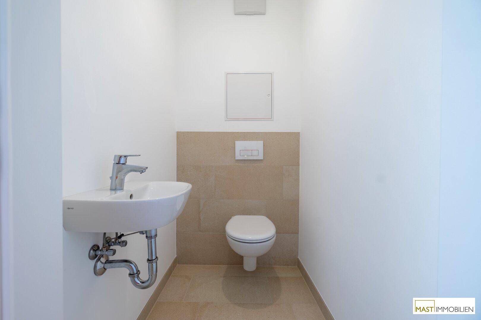Modernes Gäste-WC mit wandhängender Toilette und kleinem Waschbecken.