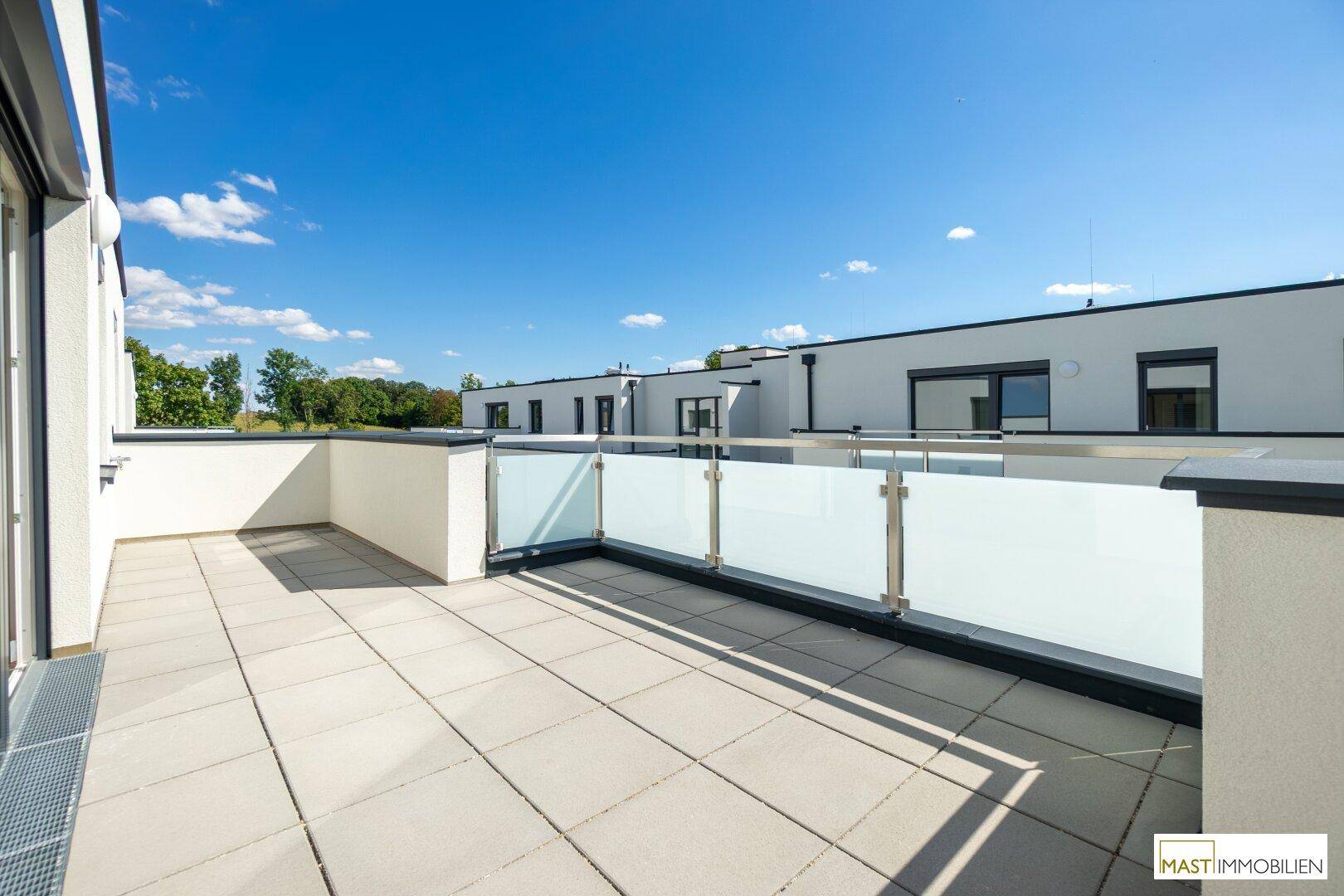 Weitläufige Terrasse mit moderner Glasbrüstung und Blick auf die umliegenden Gebäude.