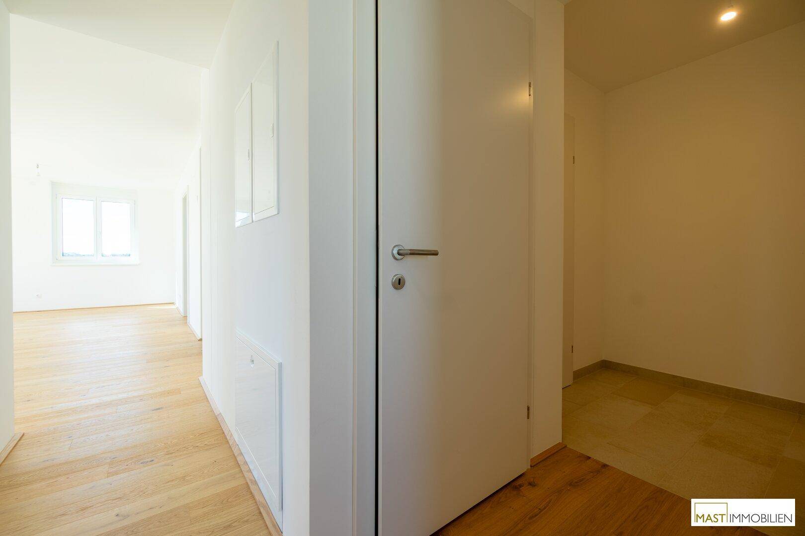 Heller Flur mit Holzboden, der verschiedene Räume der Wohnung verbindet.