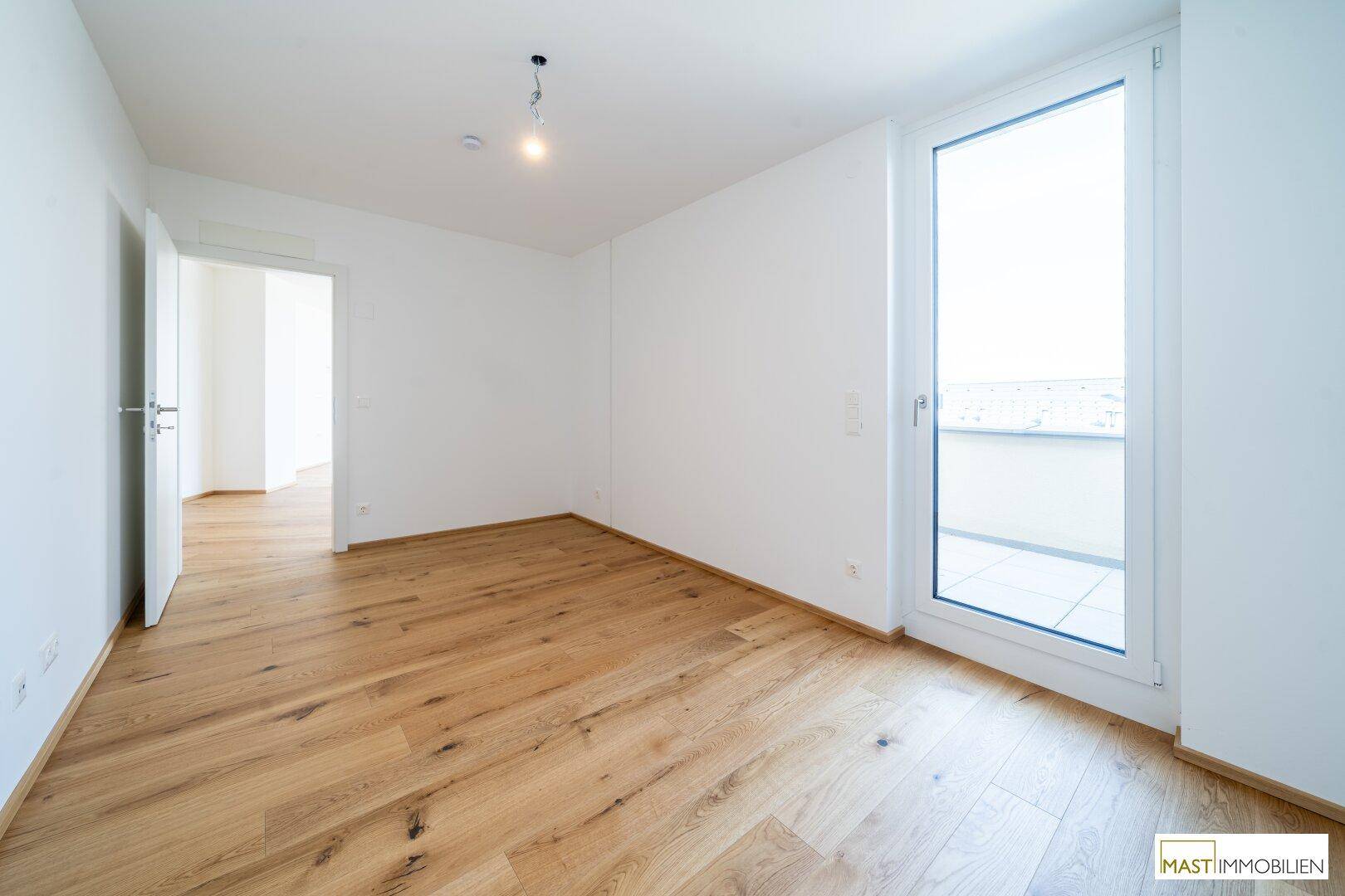 Helles Schlafzimmer mit Holzboden und direktem Zugang zu einem Außenbereich.