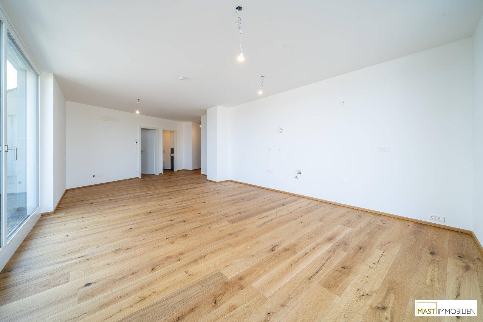 Geräumiges, helles Wohnzimmer mit elegantem Holzboden und großen Fensterfronten.