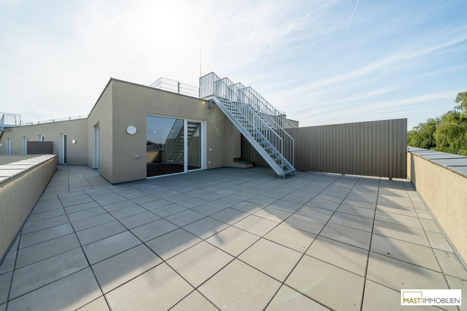 Weitläufige Dachterrasse mit moderner Architektur und Zugang zu weiteren Ebenen.
