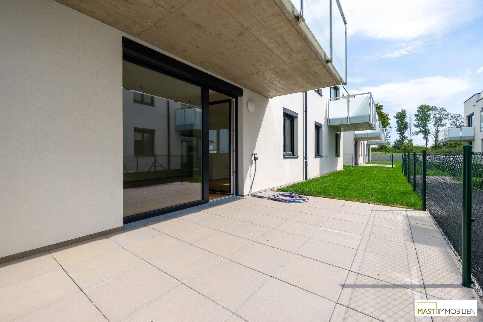 Große geflieste Terrasse mit direktem Zugang zum Innenbereich und Blick auf den Garten.