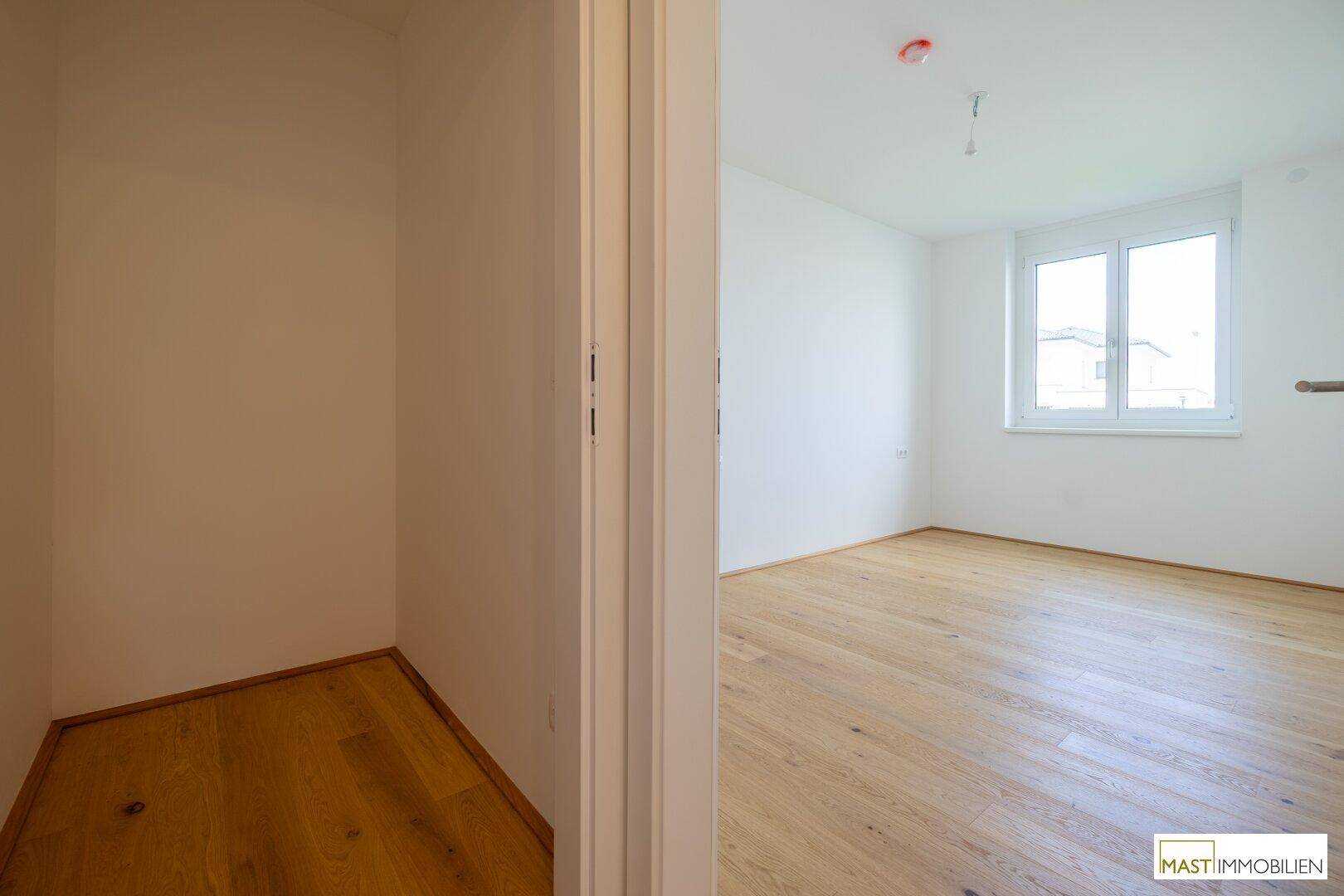 Schlafzimmer mit Holzboden und angrenzendem Abstellbereich, bietet praktischen Stauraum.