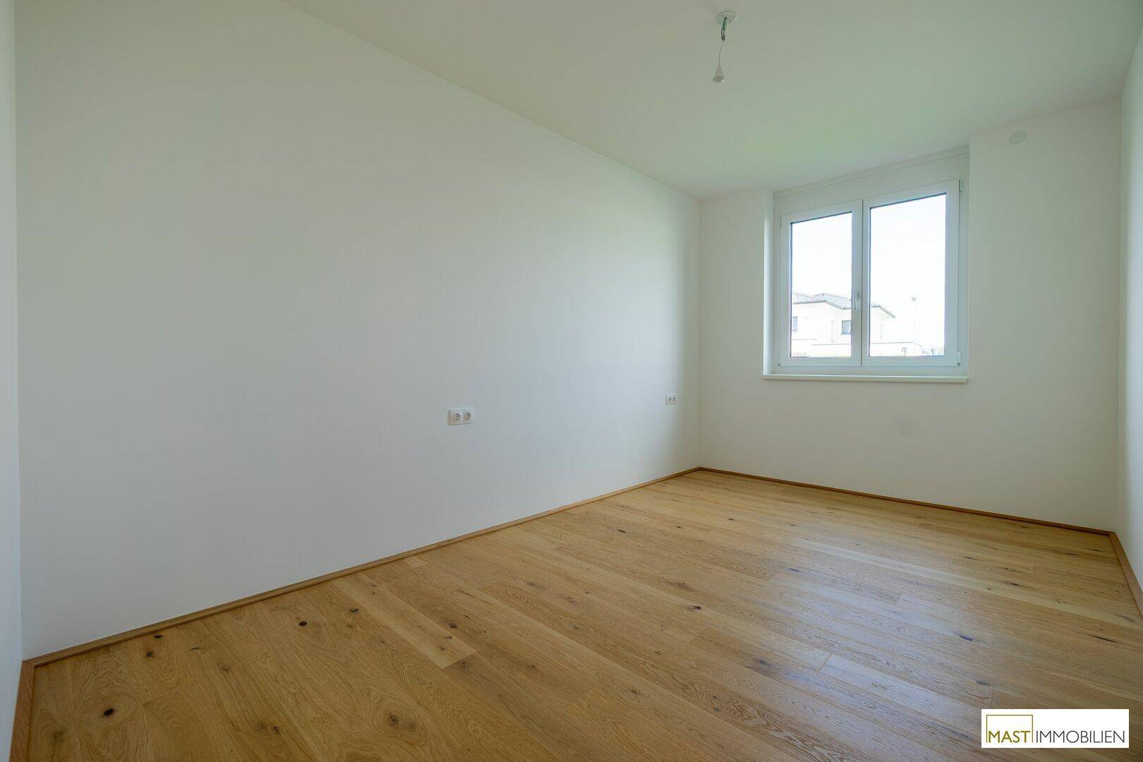 Helles Schlafzimmer mit Holzboden und Fenster mit Blick auf die Umgebung, sehr einladend.