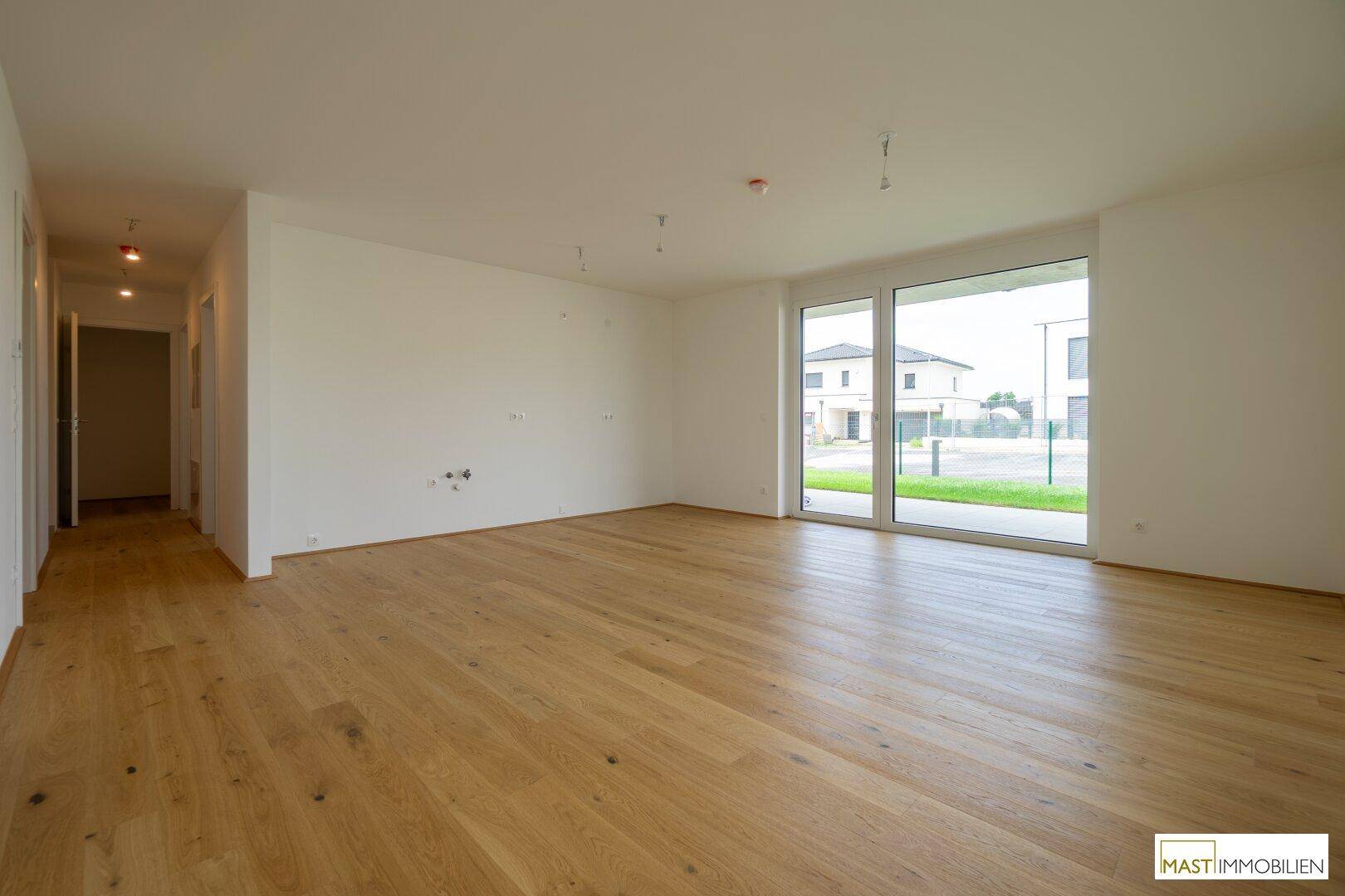 Geräumiges Wohnzimmer mit Holzboden und Zugang zum Flur, ideal für individuelle Gestaltung.