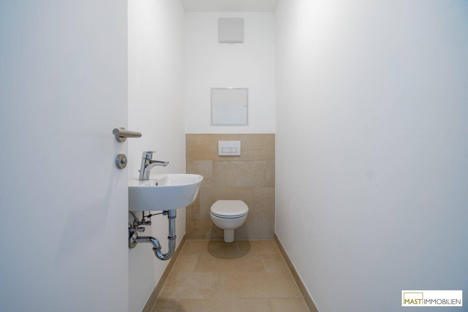 Kleines Gäste-WC mit Wand-WC und Handwaschbecken, ausgestattet mit modernen Fliesen.